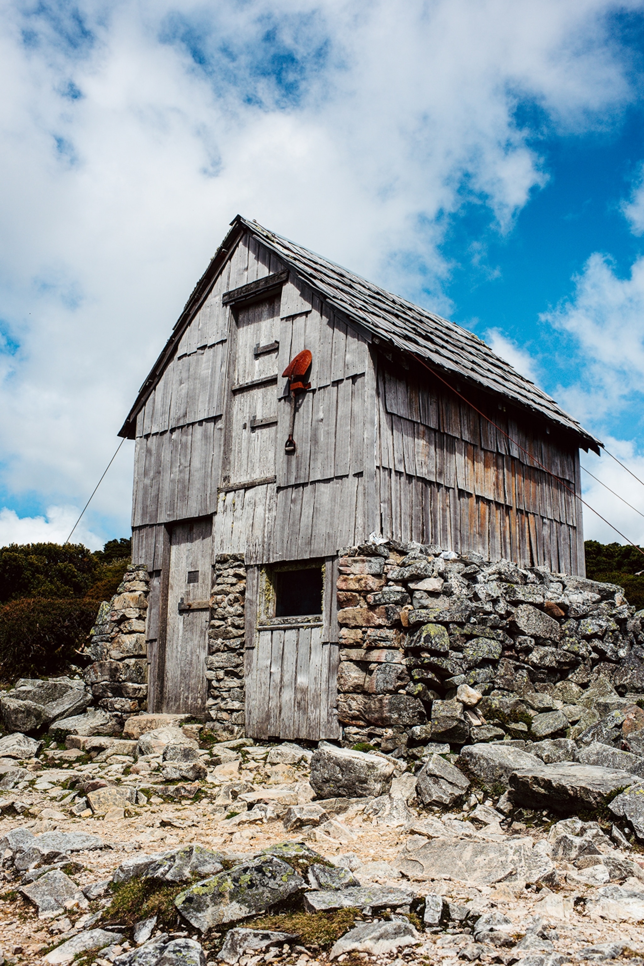 A simple, wooden hut on a rocky mountain plateau.