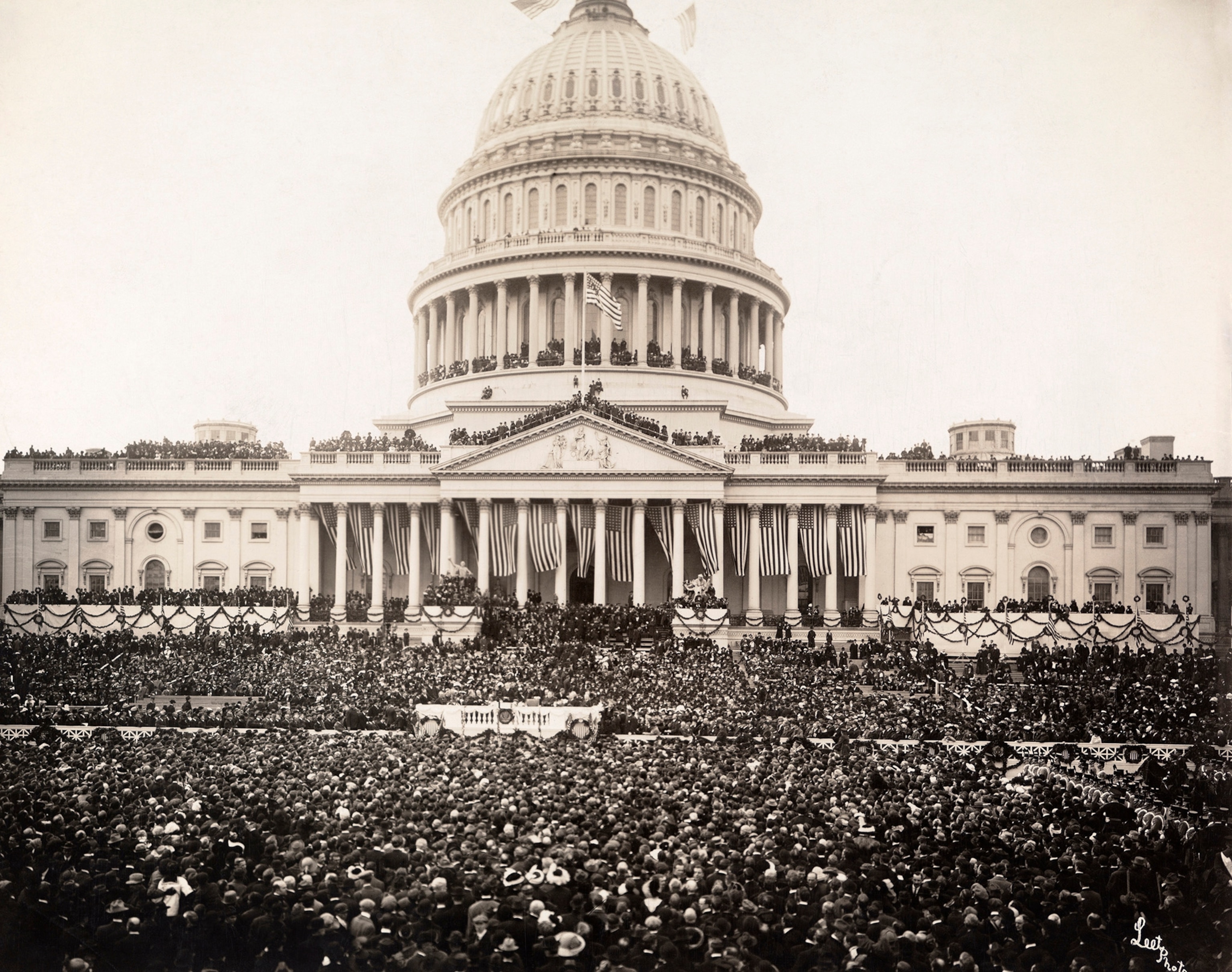 A black and white image of a large crowd of people massing in front of the United States Capitol building.
