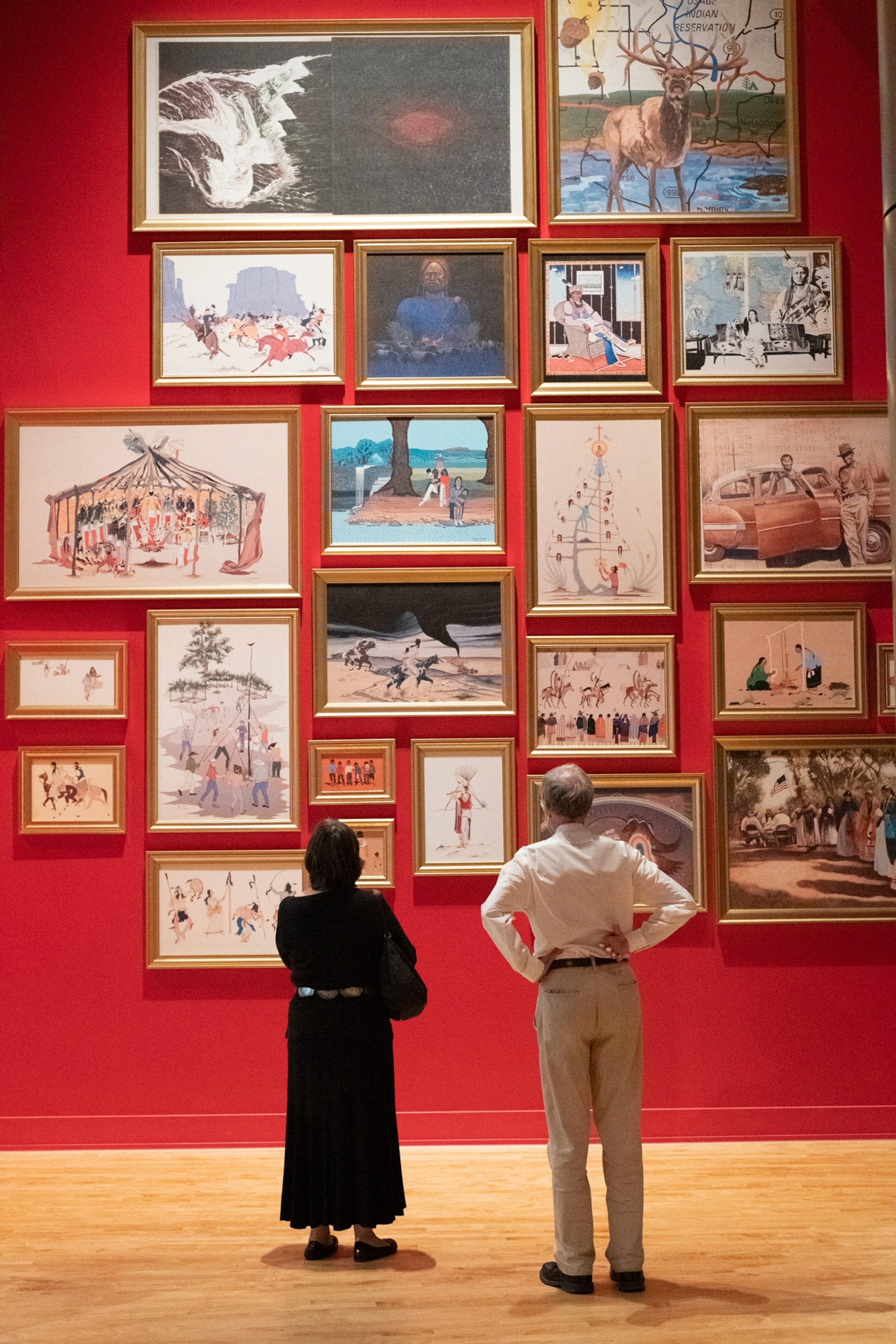 Two adults look at OKLA HOMMA gallery art