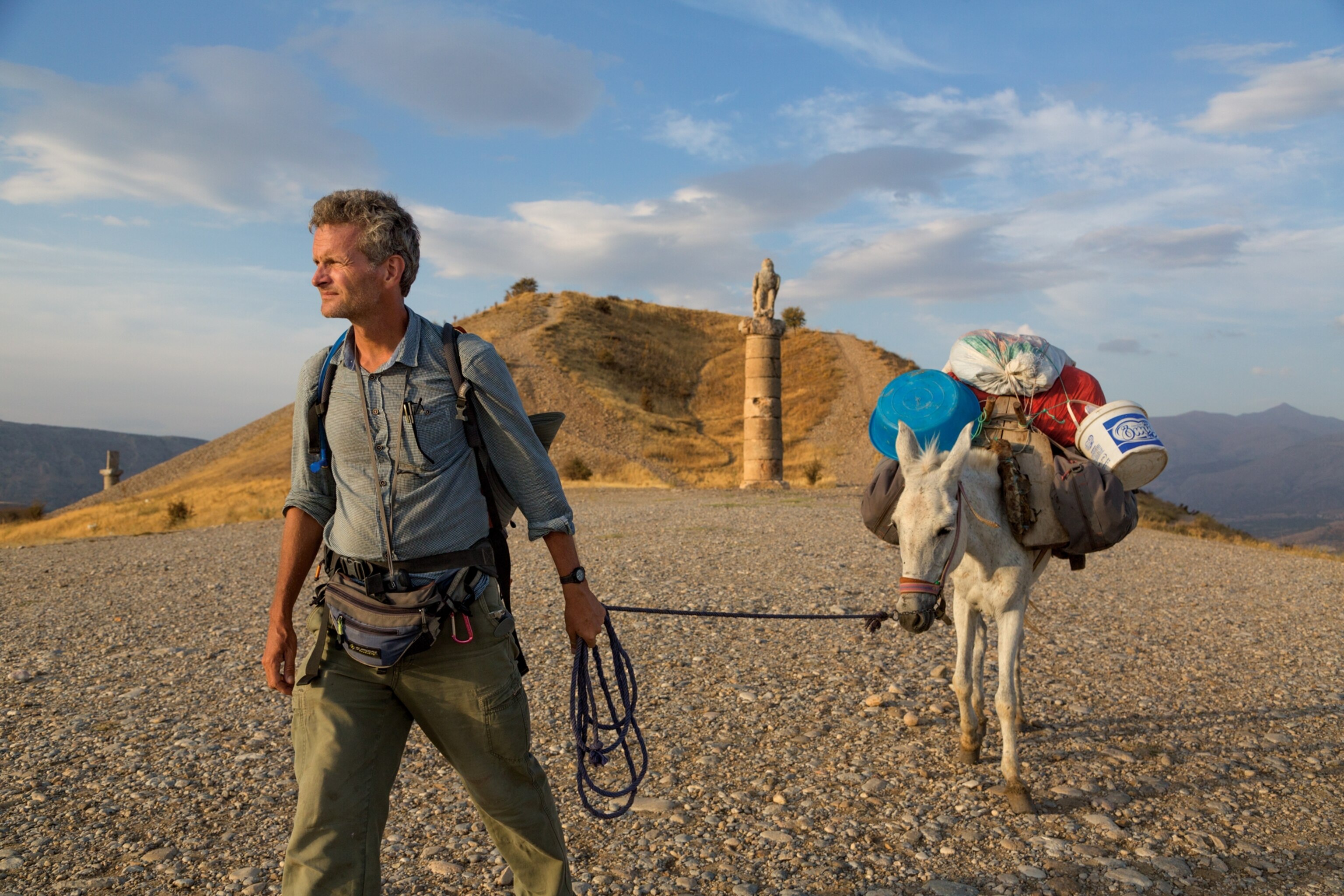 Paul Salopek leading a mule past a tomb in eastern Turkey