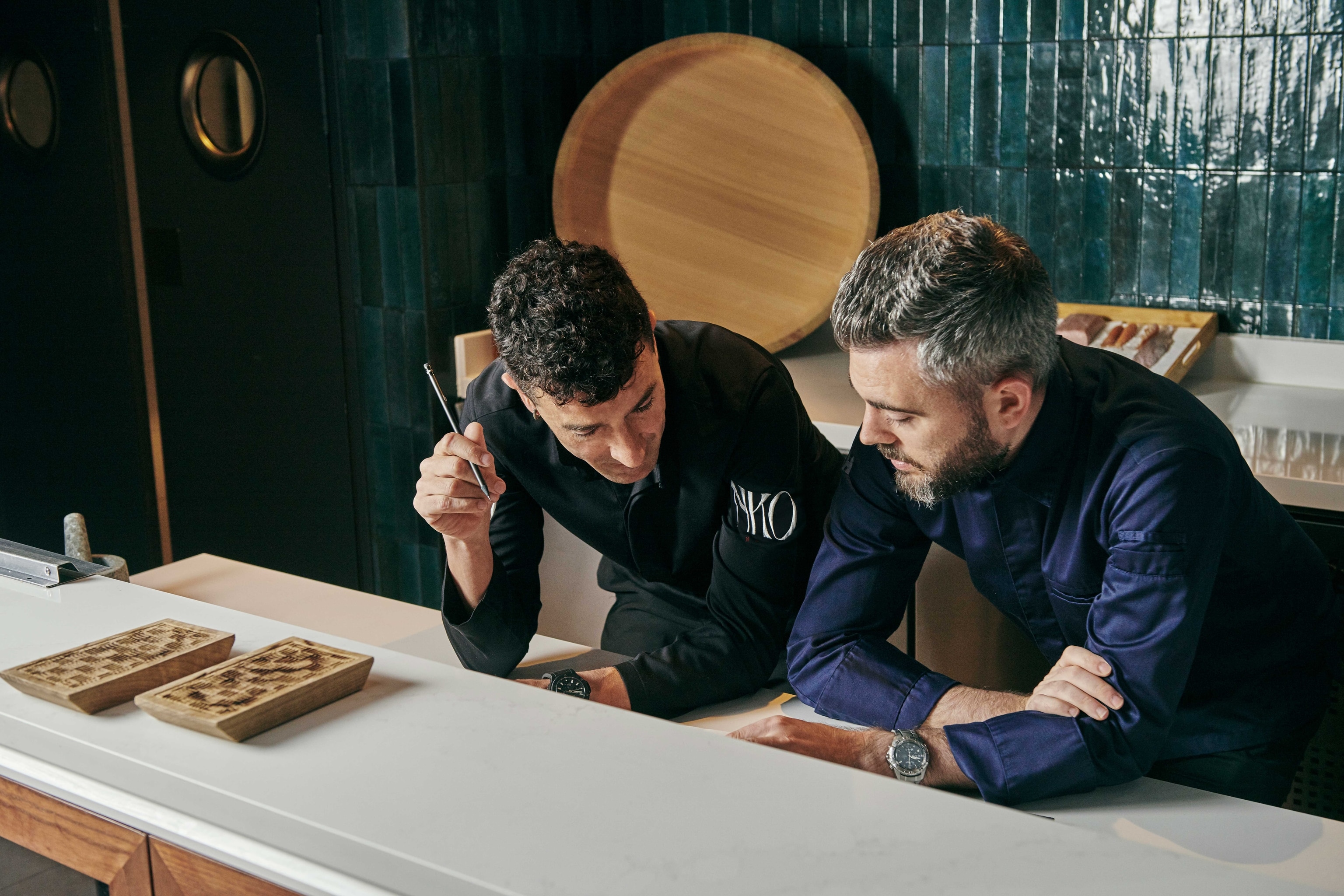 Chef Eneko Atxa leans across a counter discussing with a colleague