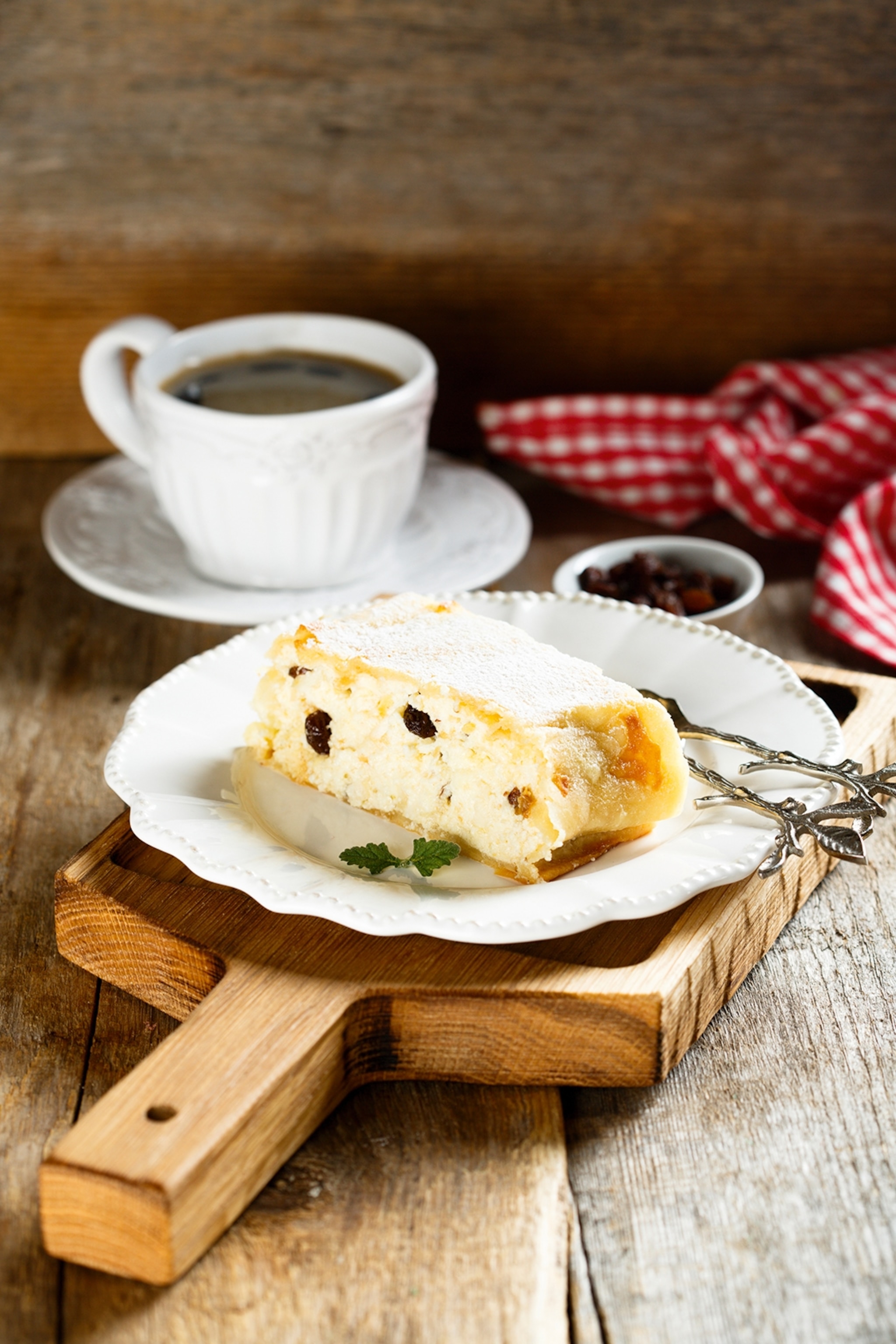 A plate of strudel with cottage cheese on a wooden board with a cup of coffee in the background.