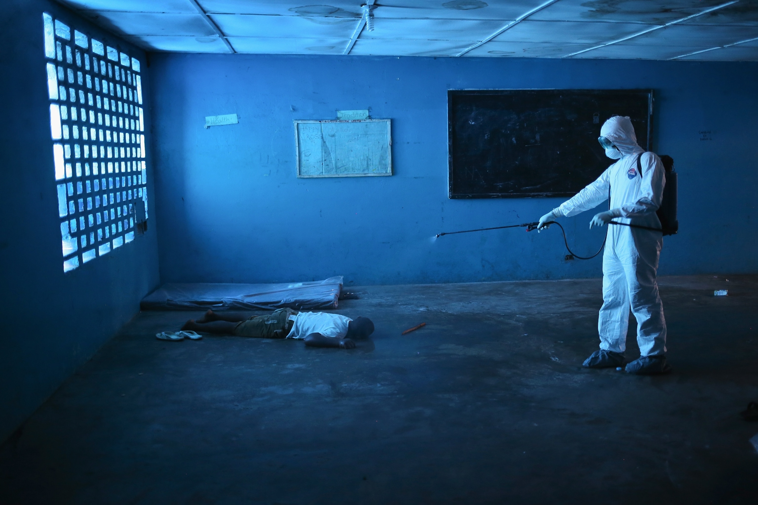 a Liberian health worker disinfecting a corpse after the man died.
