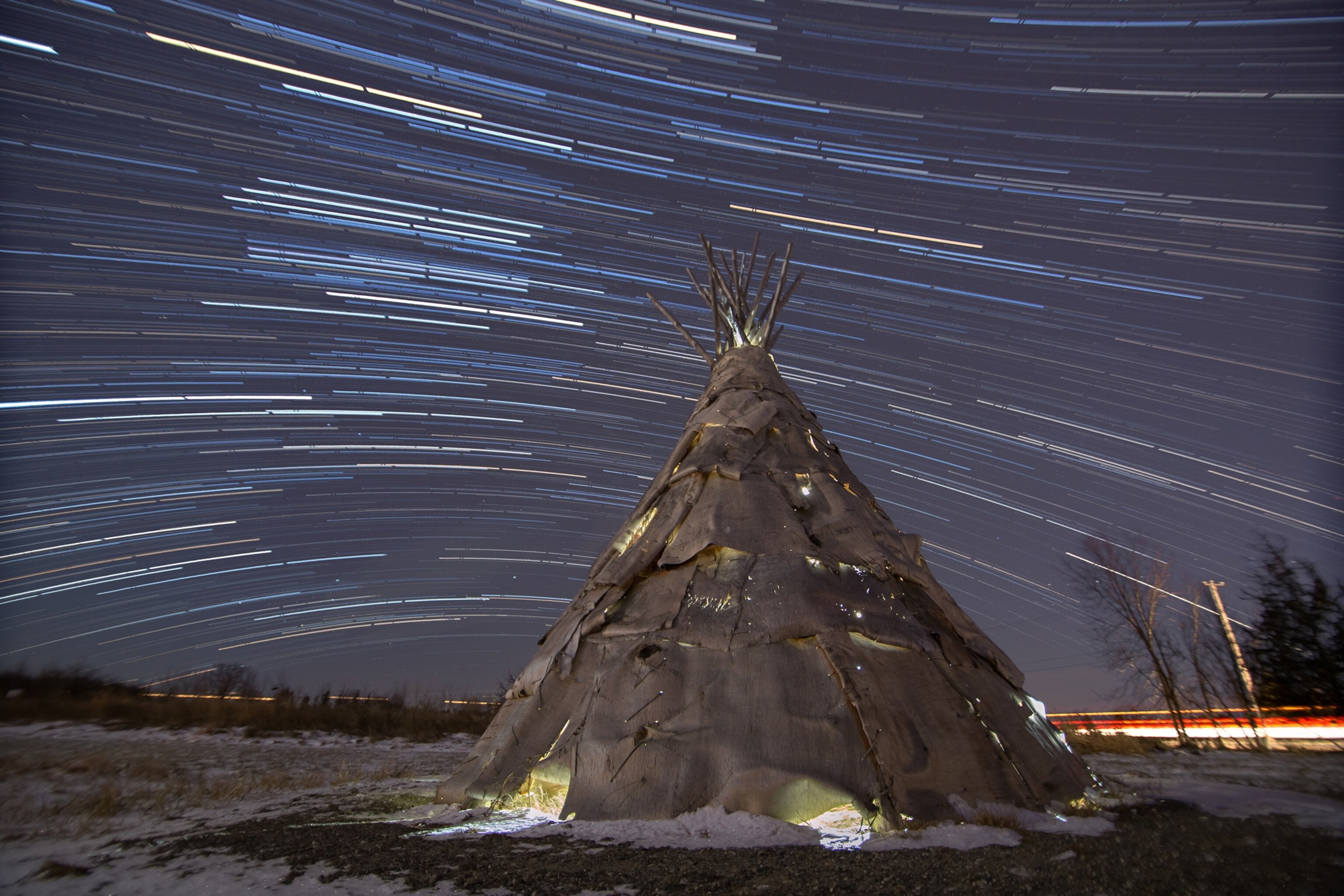 a birch bark, hand made Abenaki tee-pee with star trails in the background.