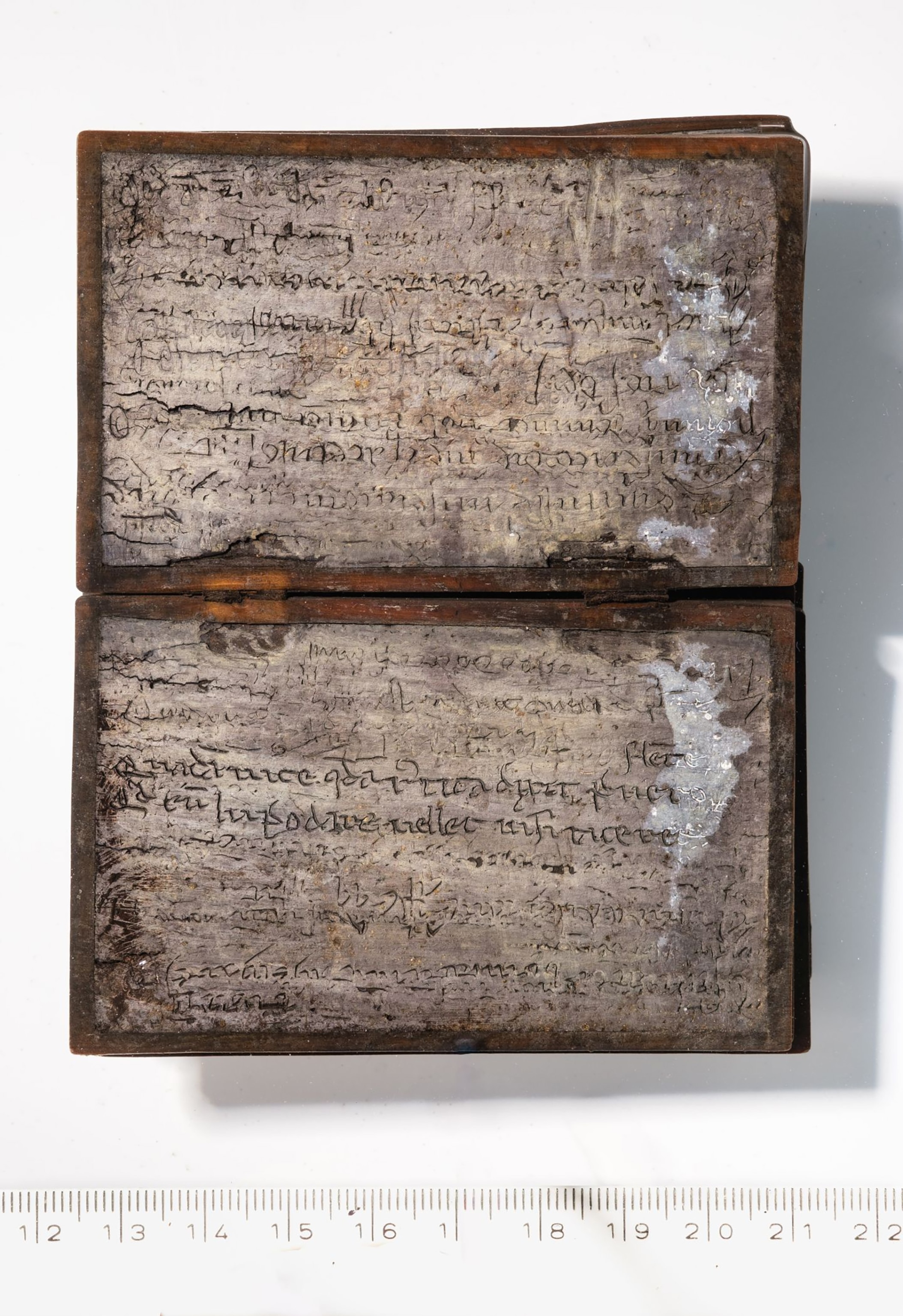 Wood-framed gray paper with latin writing displayed open.