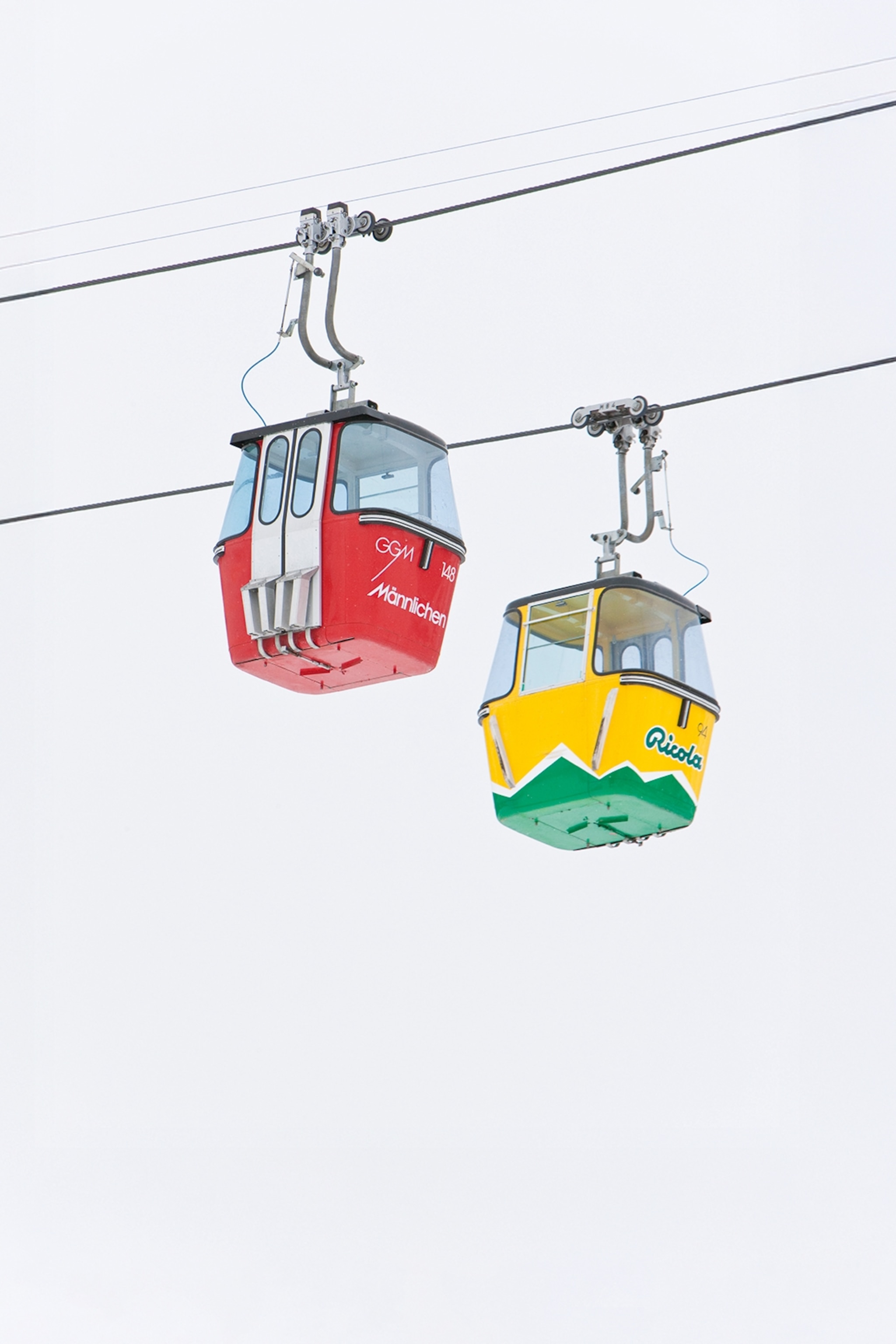 Two gondolas passing each other in the foggy winter sky.