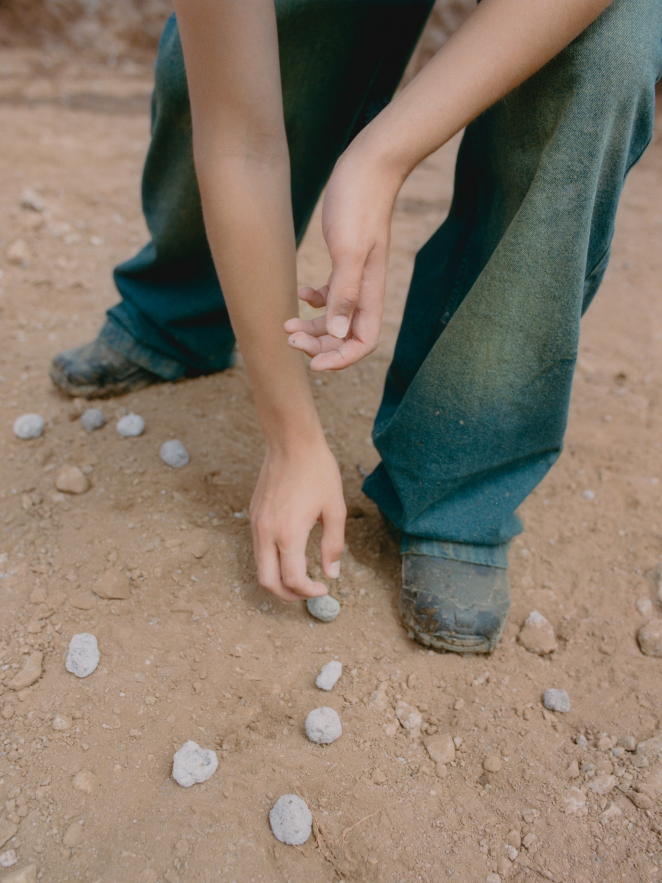 A person's hands reach down to arrange seed bombs in lot.