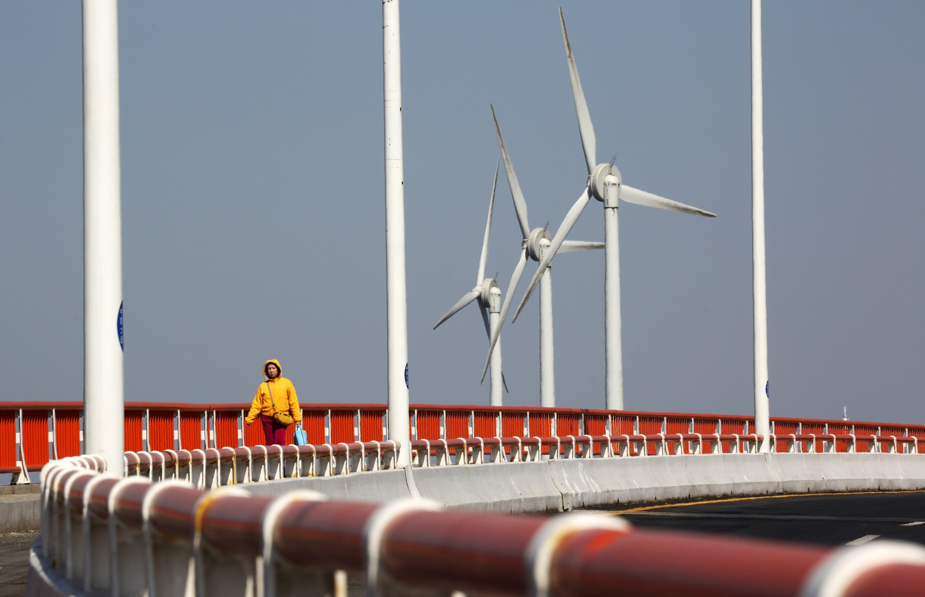 a pedestrian walking on a bridge in front of wind turbines at the Sino-Singapore Tianjin Eco-city.