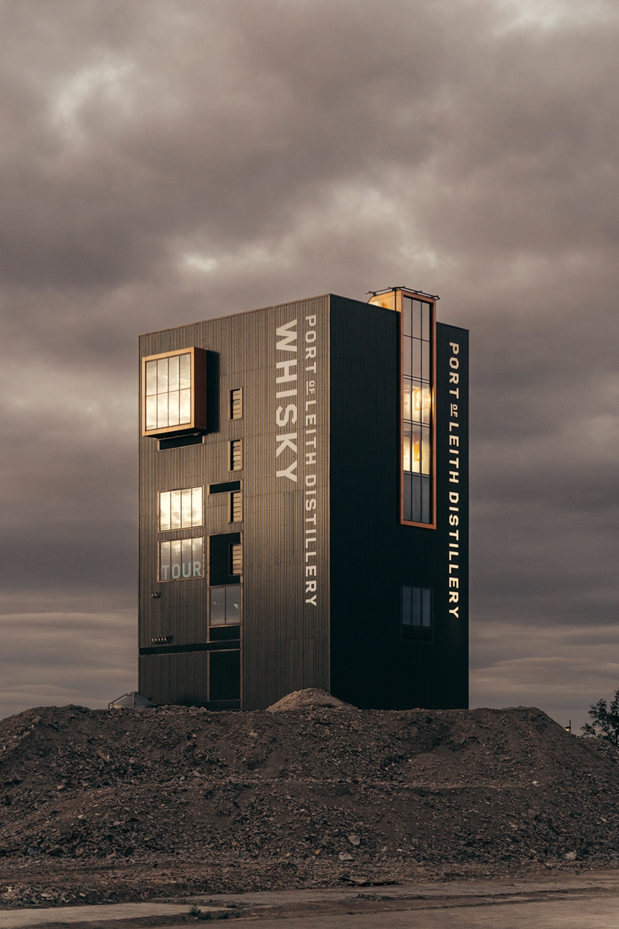 A single vertical block building with strategically placed windows in front of a cloudy sky.