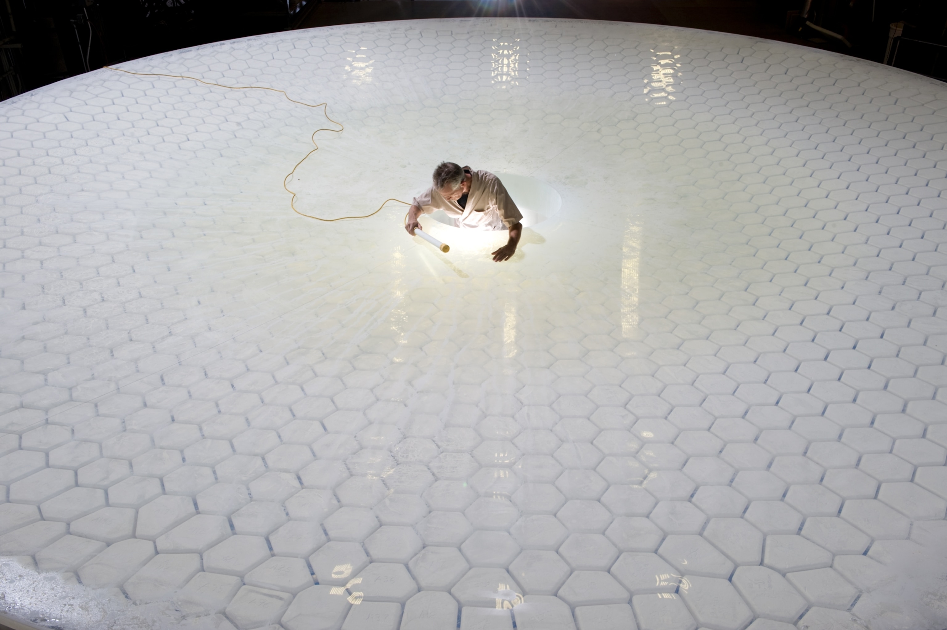 a technician poring over the surface of the Large Synoptic Survey Telescope mirror