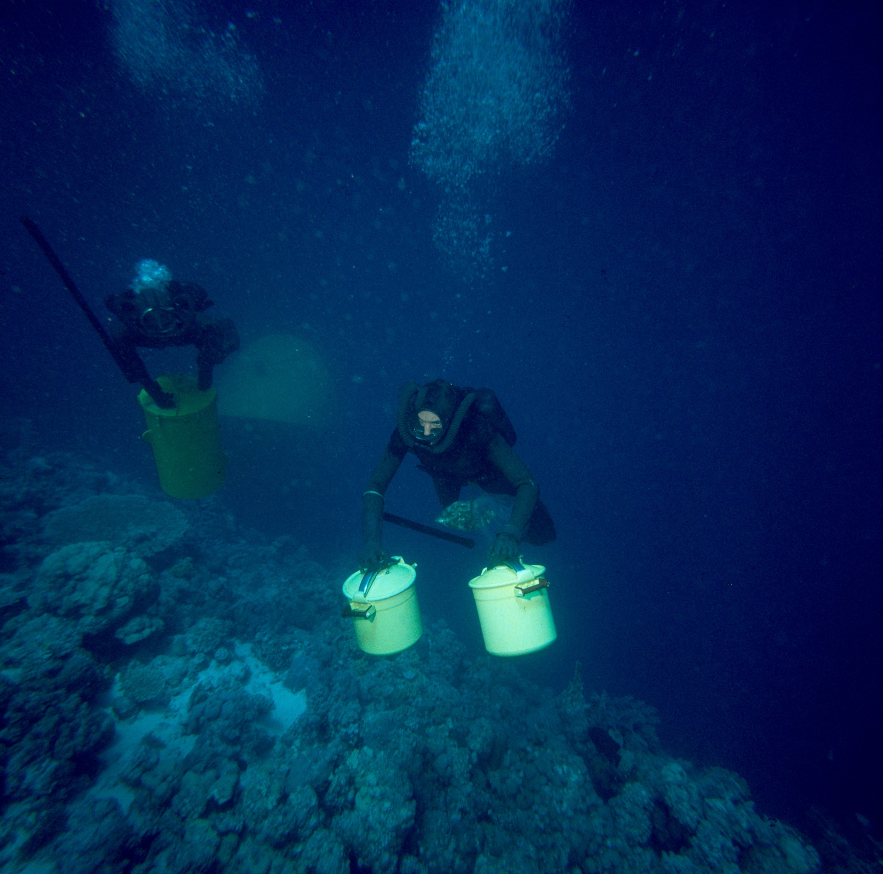 Men carry supplies in sealed pots to and from a submersible.