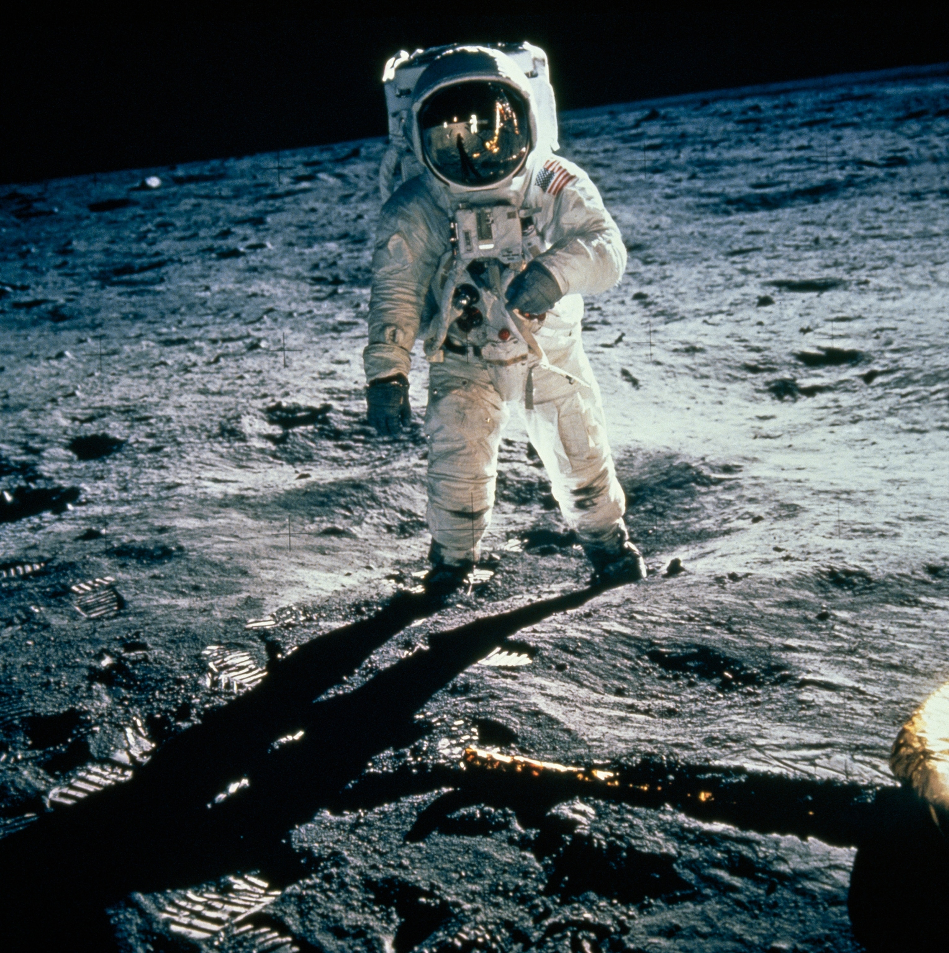 At dawn of a two-week lunar day, Edwin Aldrin strides across a small crater near one of Eagle's foil-wrapped landing probes. Visor reflects his long black shadow, the solar wind collector, the Stars and Stripes planted by the moonwalkers, the white figure of Armstrong (who took this picture), and the buglike lunar module. A few hours earlier the two men had flashed the words that thrilled a waiting world: "Tranquillity Base here. The Eagle has landed." While Armstrong and Aldrin explore the surface, Michael Collins keeps lonely vigil in Columbia, Apollo 11's command module orbiting the moon.