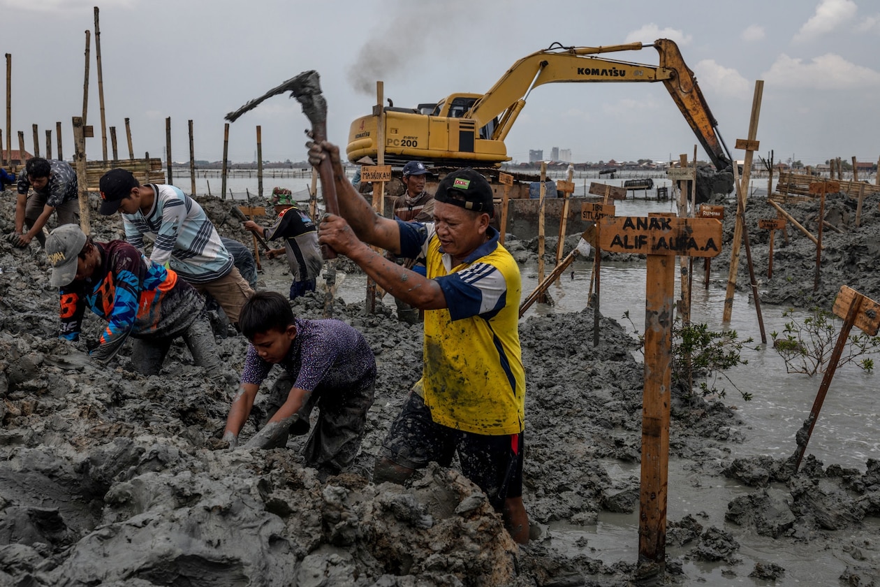 Villagers spread mud on a flooded cemetery.