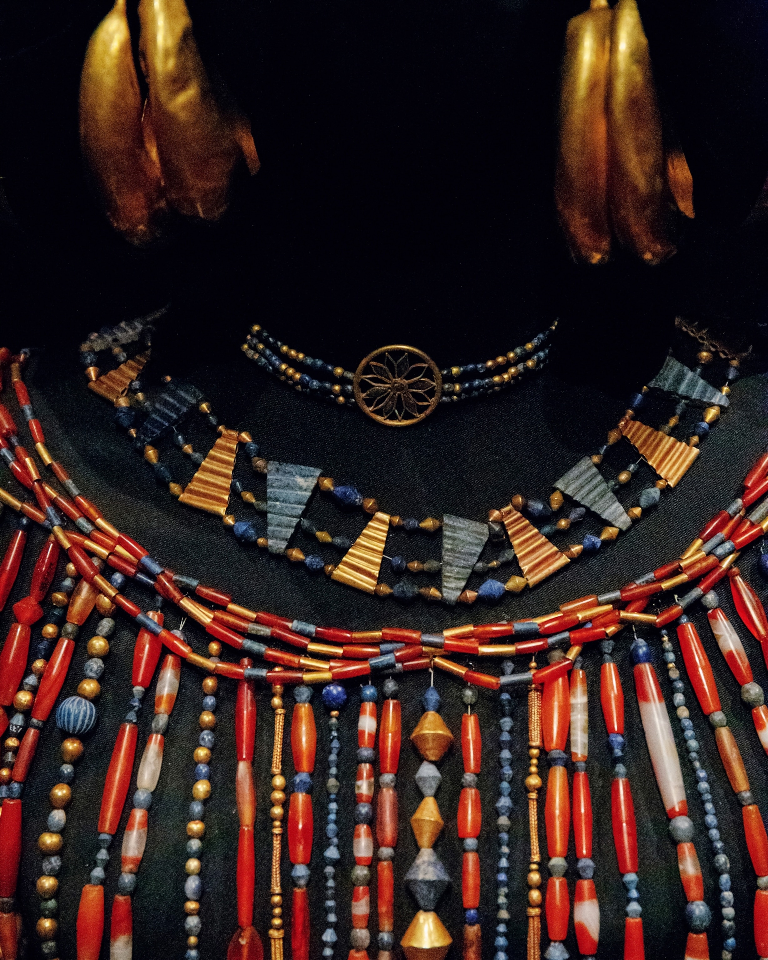 Ancient jewelry display featuring gold, blue, and red beads in intricate patterns.