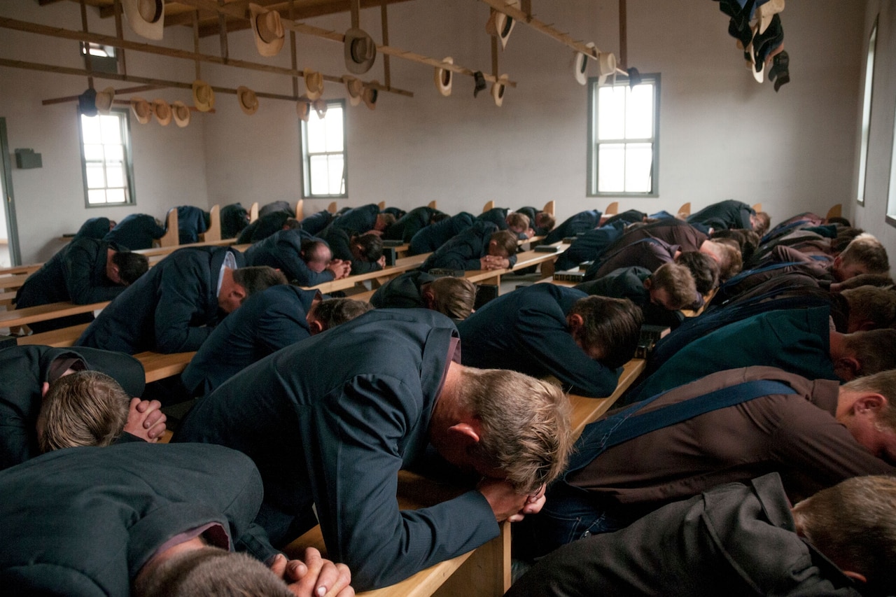 Mennonite men pray during a church service. Men sit on one side of the room and women on the other. Pinondi Colony, Bolivia. 2008
