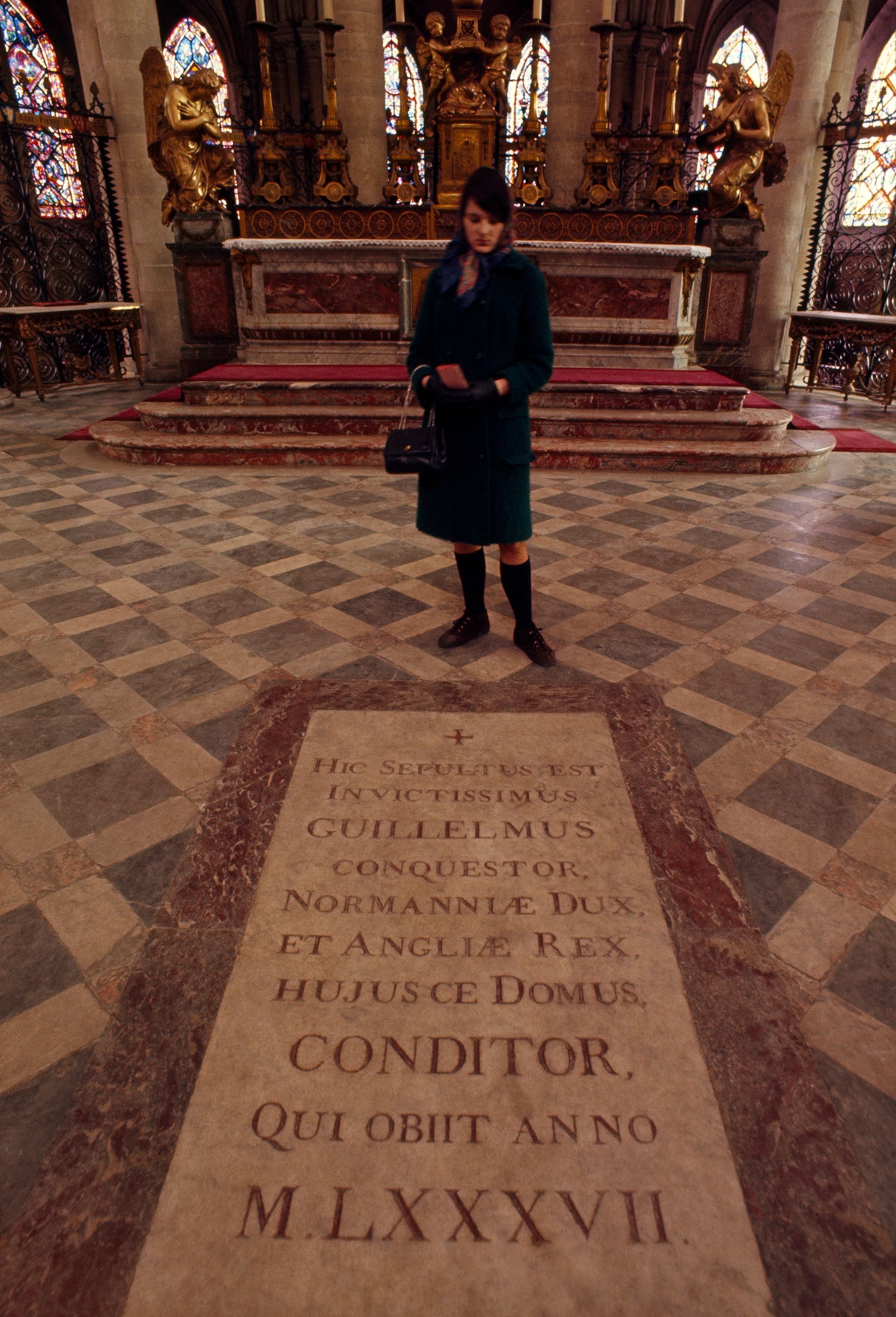 A visitor stands at a stone slab commemorating William the Conquerer.