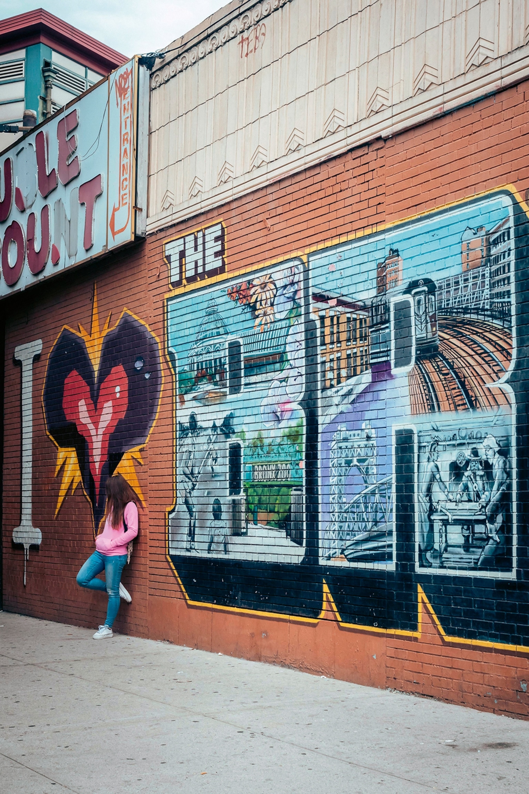 A city walk way leading past a brick wall with graffiti.