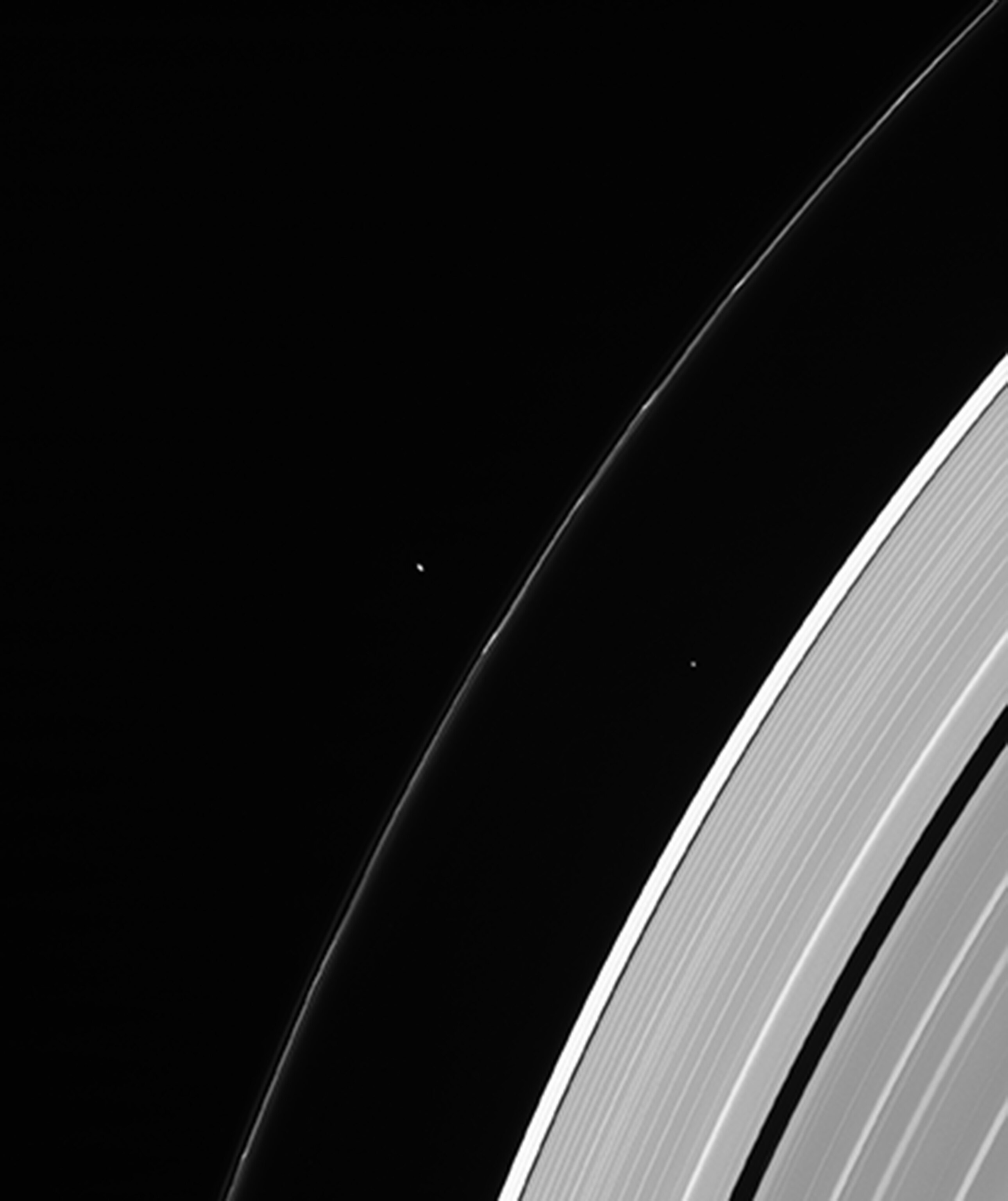 Saturn's moons appearing very small in comparison to its rings.