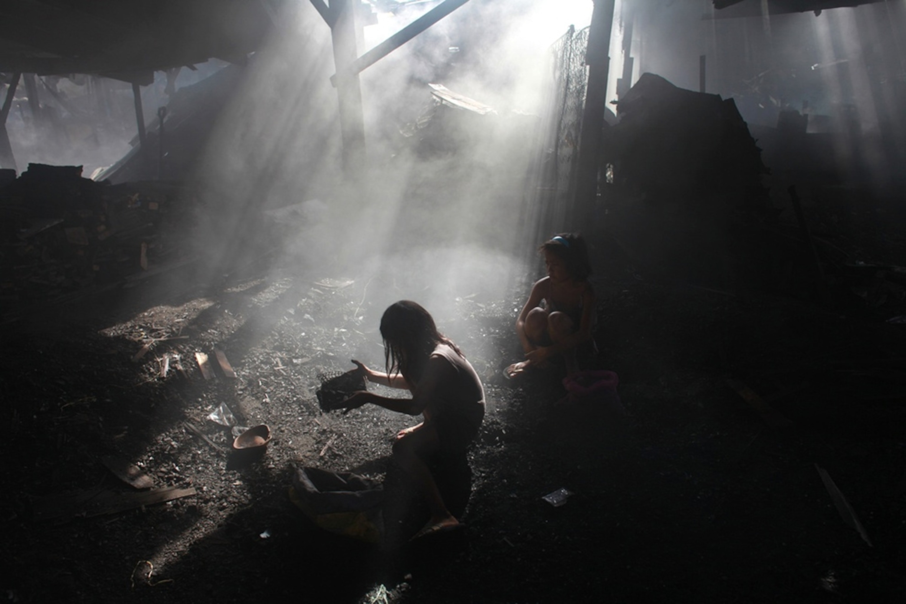 A girl searching for nails in the charcoal, Manila, Philippines