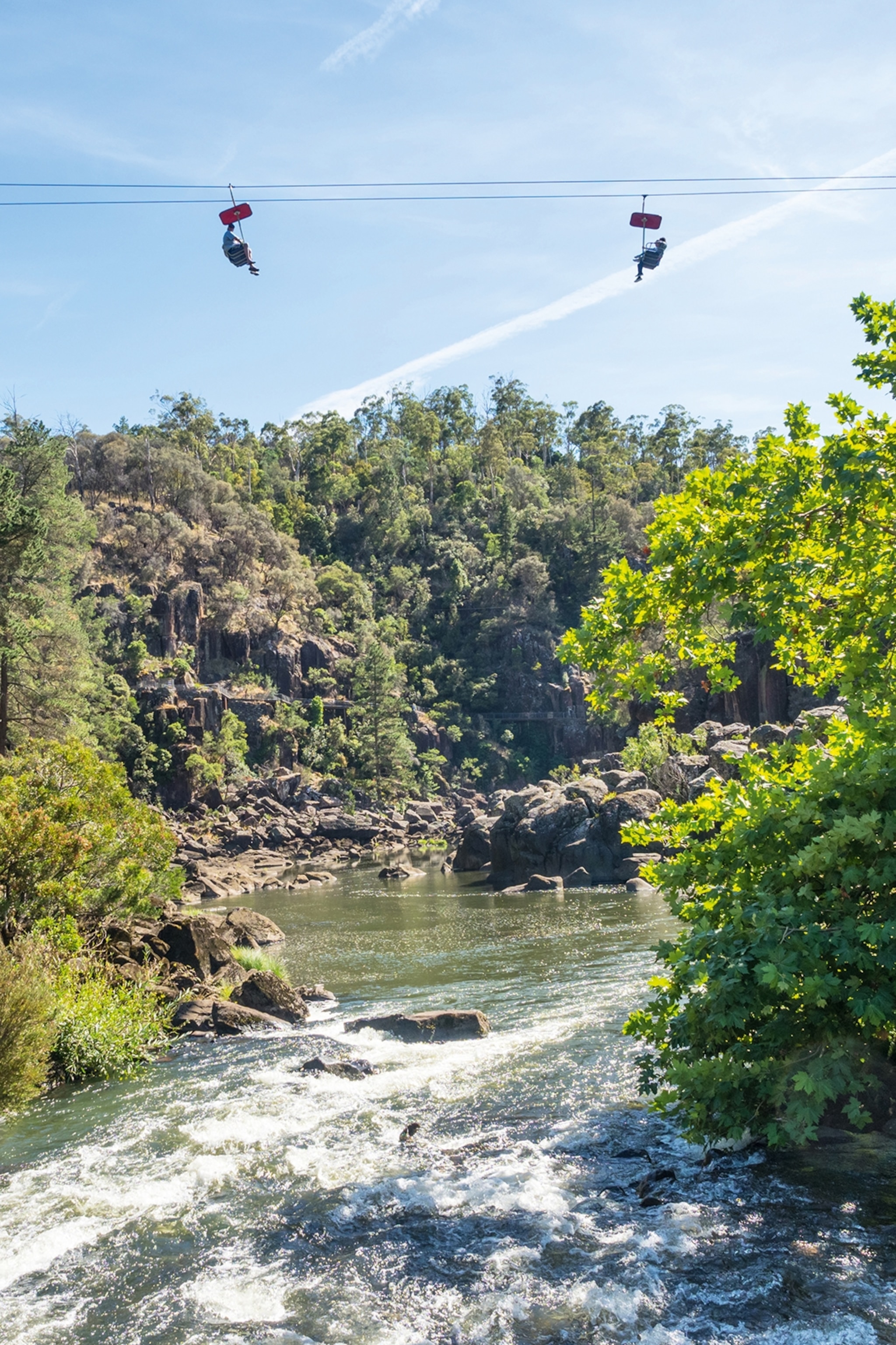 A two-seater chair lift running above a river gorge.