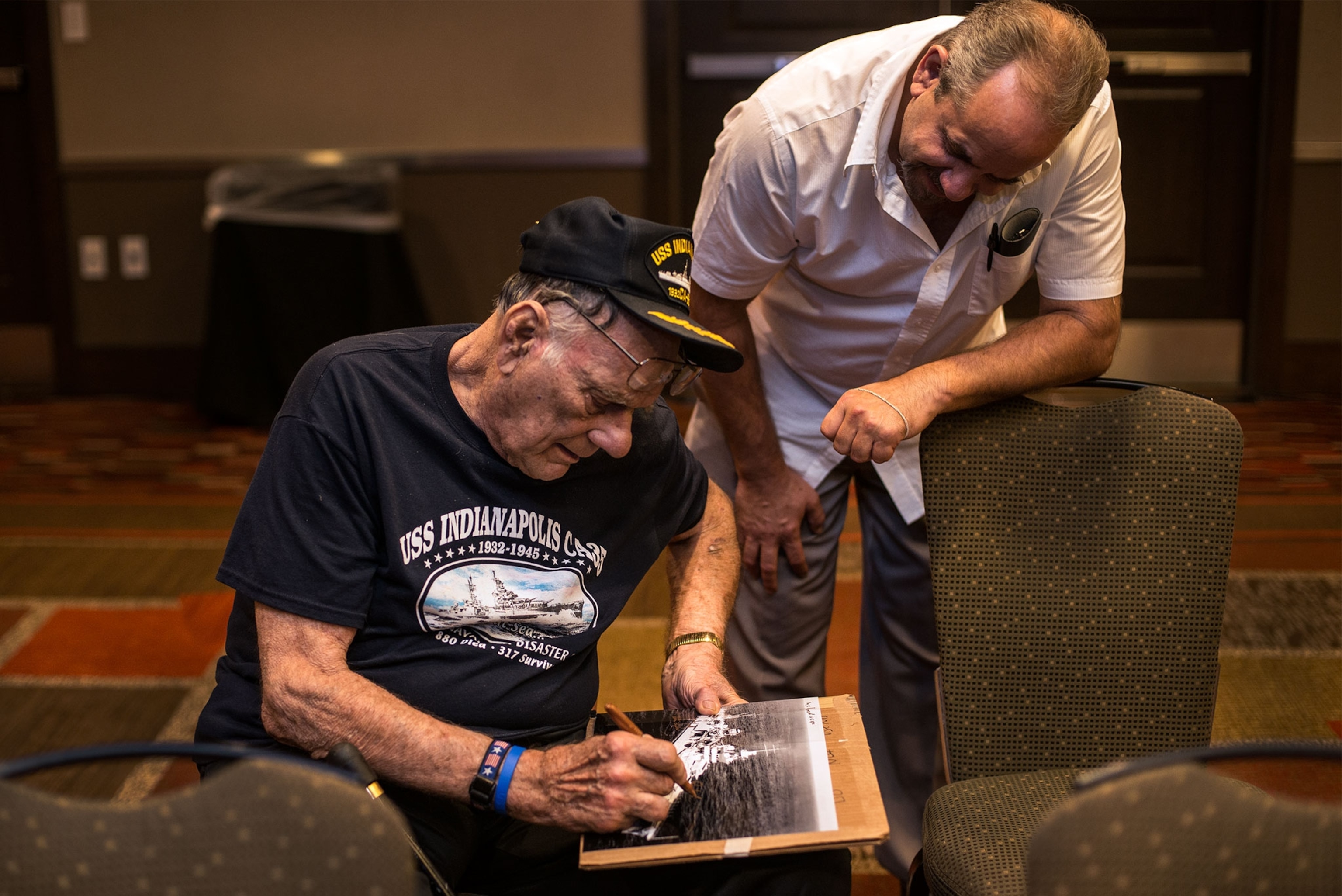 a survivor of the sinking of the USS Indianapolis signing a photo of the ship