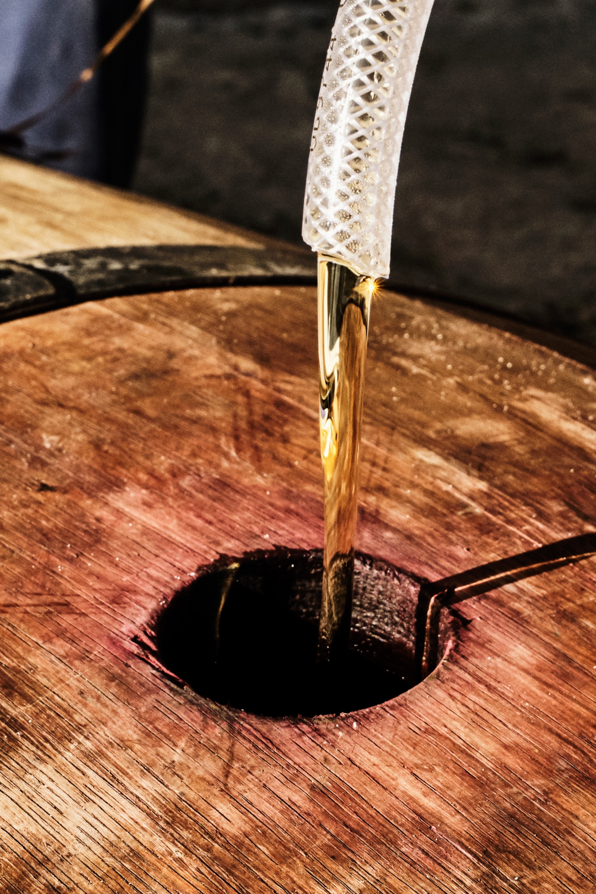 A valve of fresh rum filling up an oak barrel.