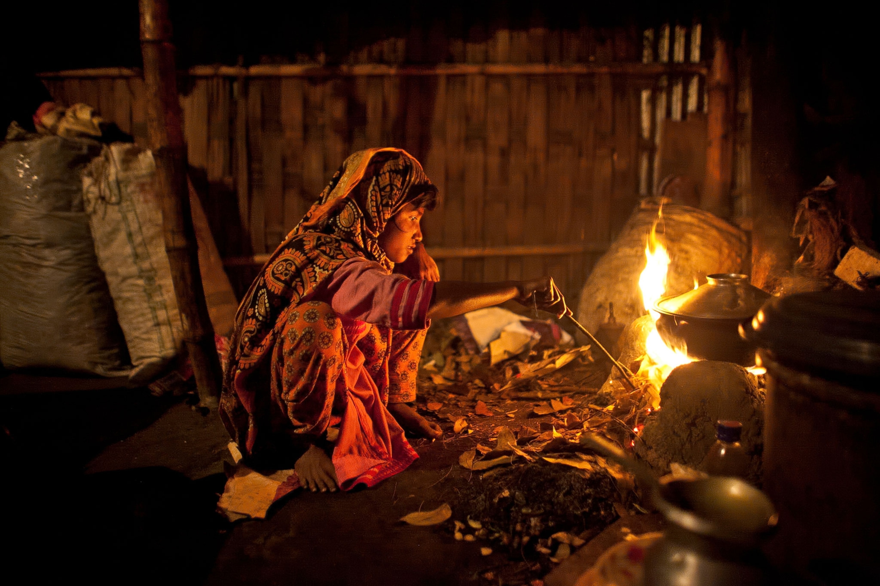 Johanara stokes a cooking fire at her home in Bangladesh.