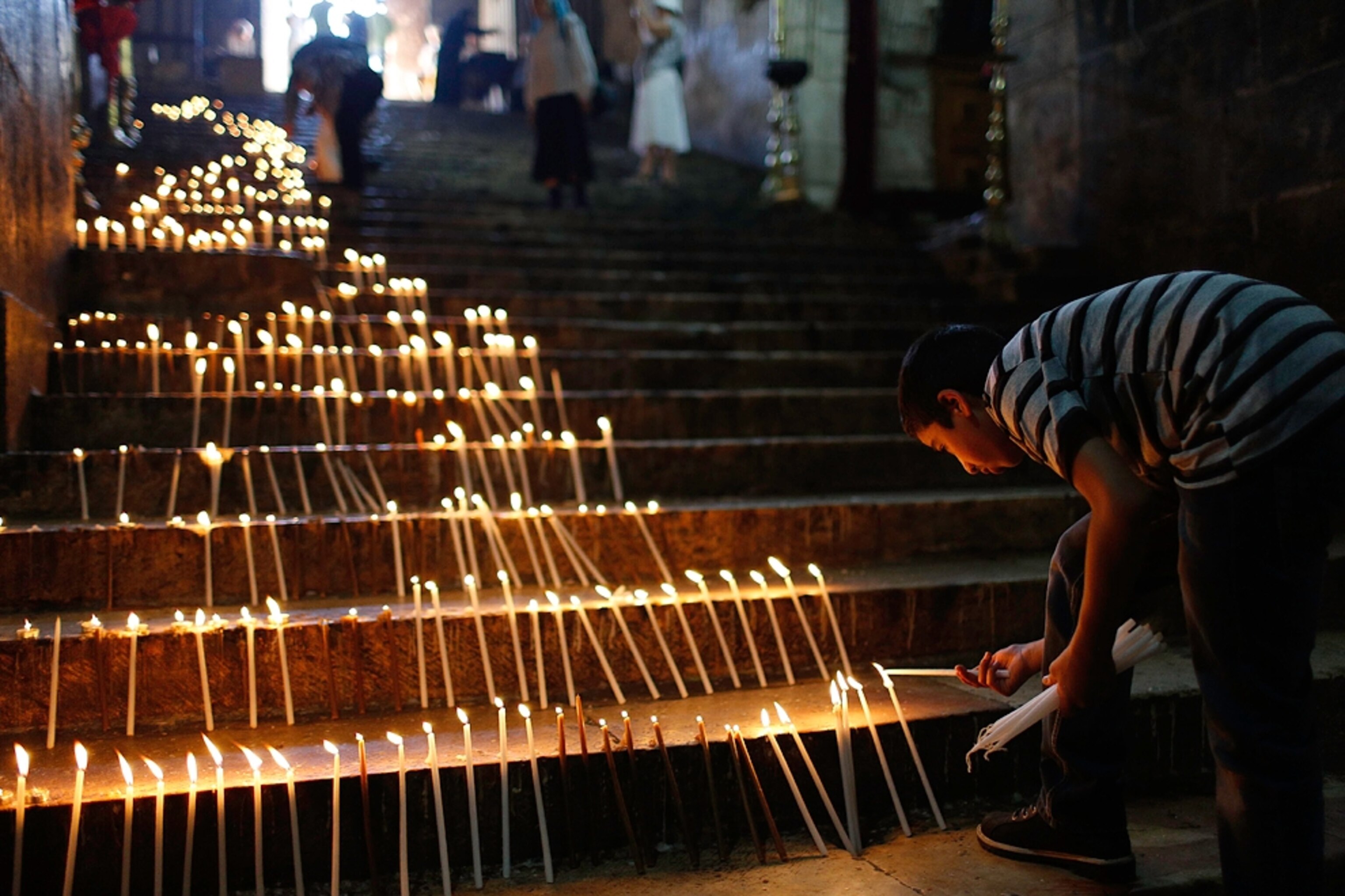 a boy lighting candles on church steps, Jerusalem