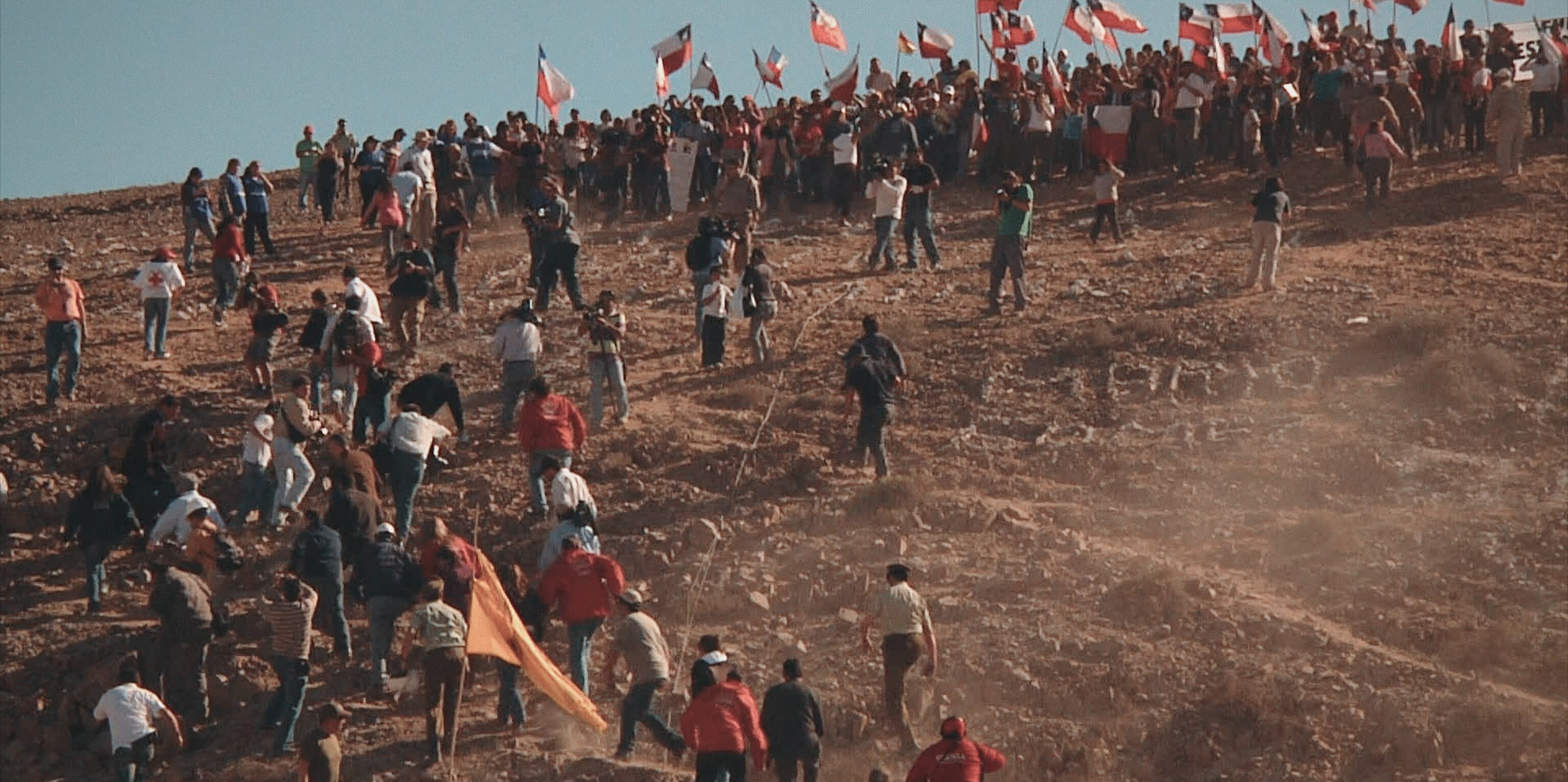 A wide photograph of many people running up a hill.