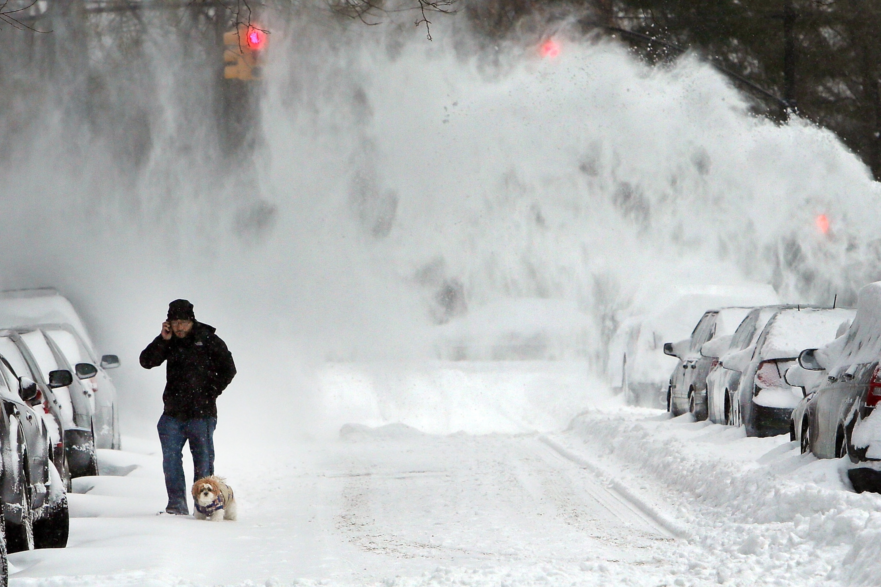 a man walking a dog in Brooklyn, New York, as snow blows behind him on Friday
