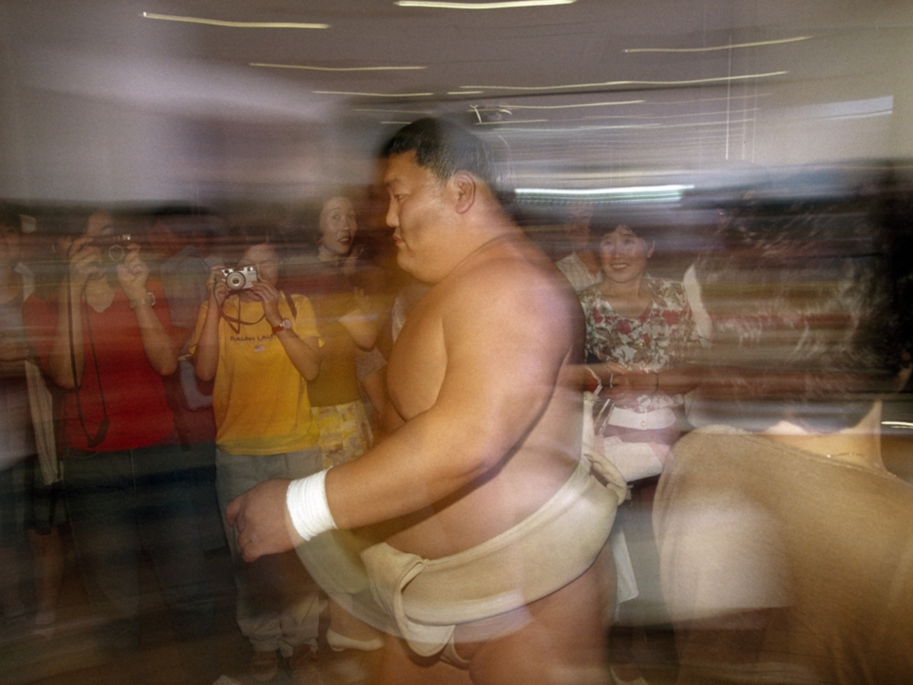 Blurred image of sumo wrestler walking past fans
