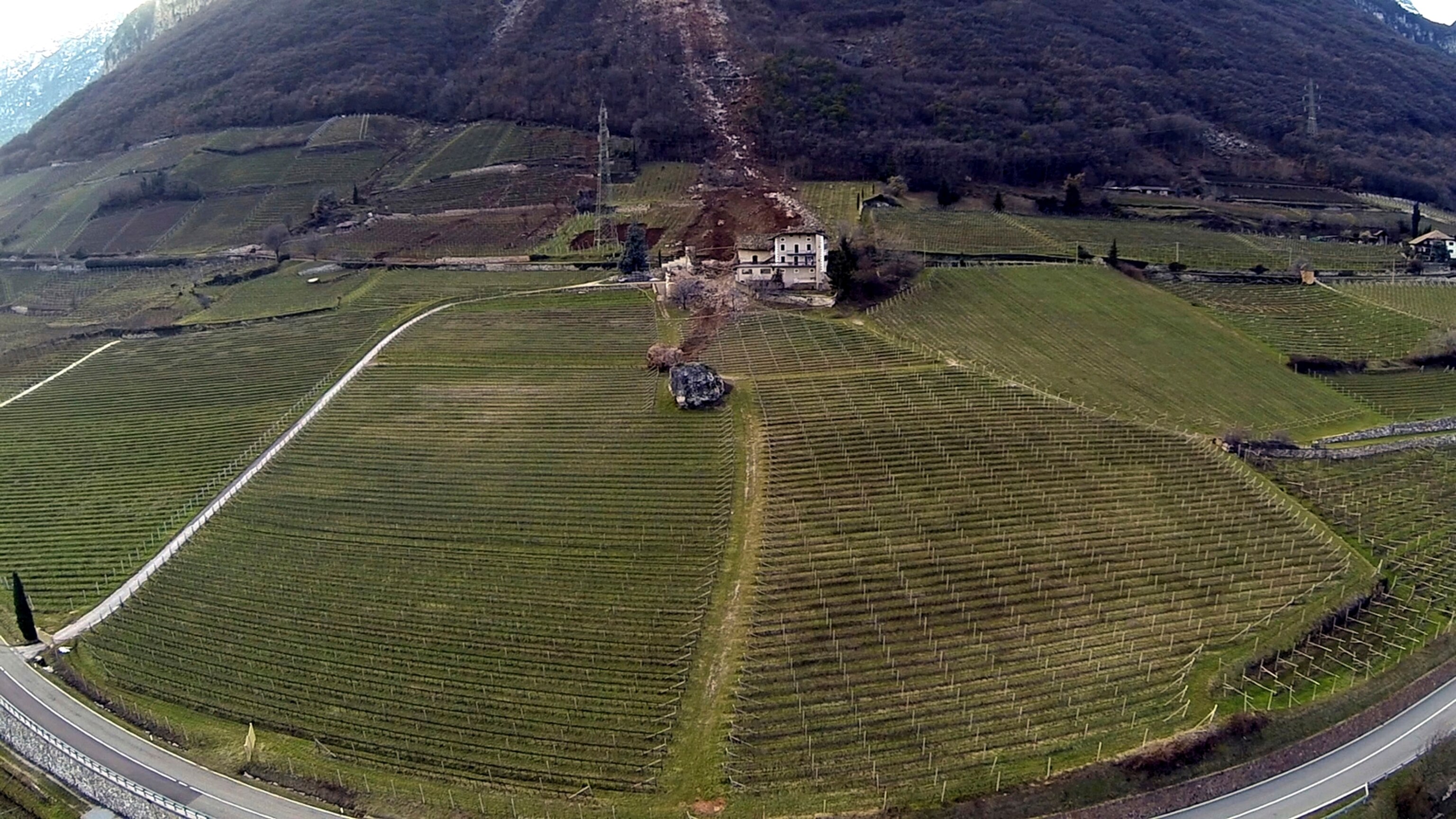 In this photo provided by Tareom.com Thursday, Jan. 30, 2014, and taken on Jan. 23, 2014, a huge boulder is seen after it missed a farm house by less than a meter, destroying the barn, and stopped in the vineyard, while a second giant boulder, which detached during the same landslide on Jan. 21, 2014, stopped next to the house, in Ronchi di Termeno, in Northern Italy.