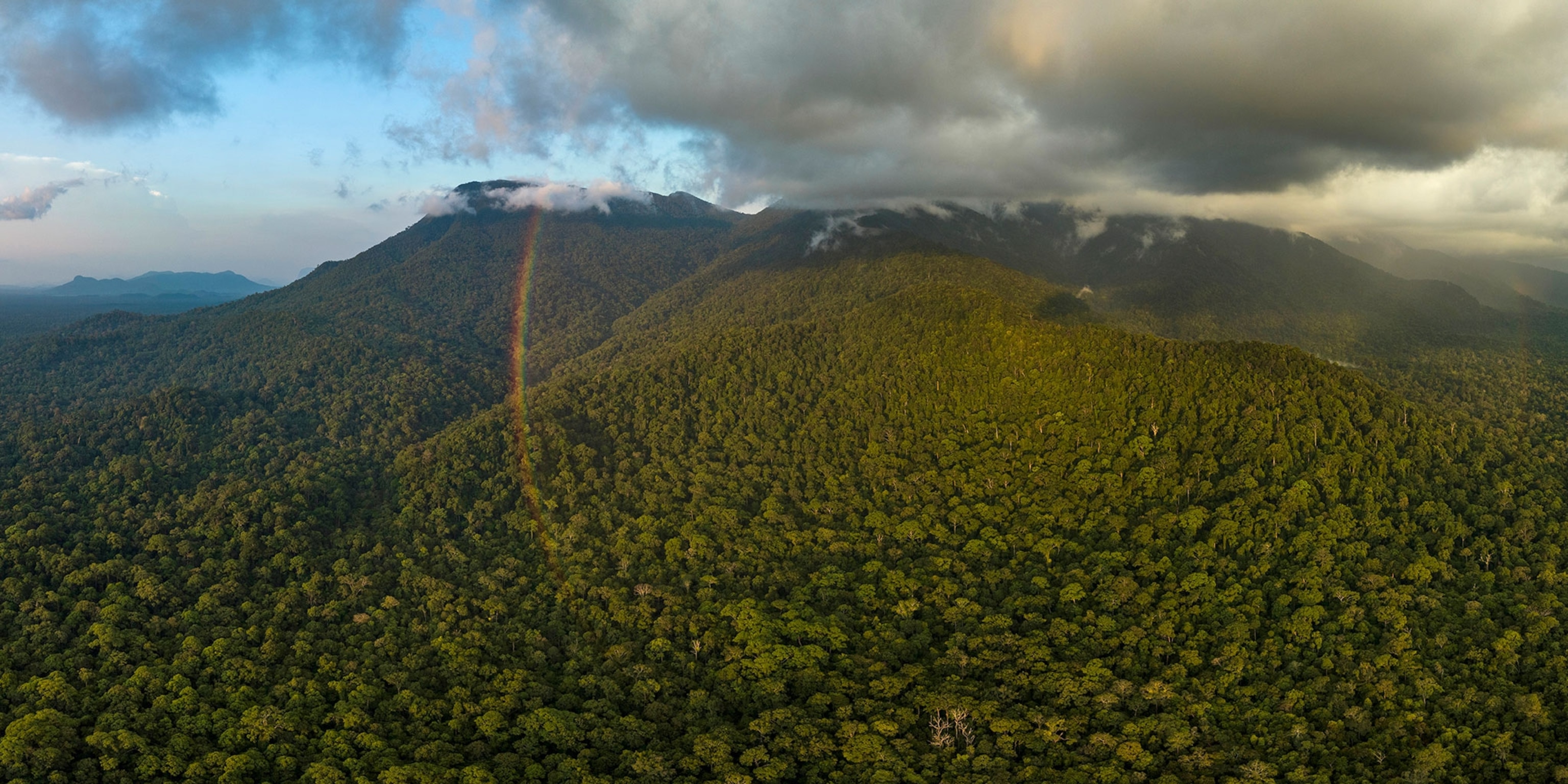 Aerial view of Mount Palung and surrounding ridges with clouds and rainbow.