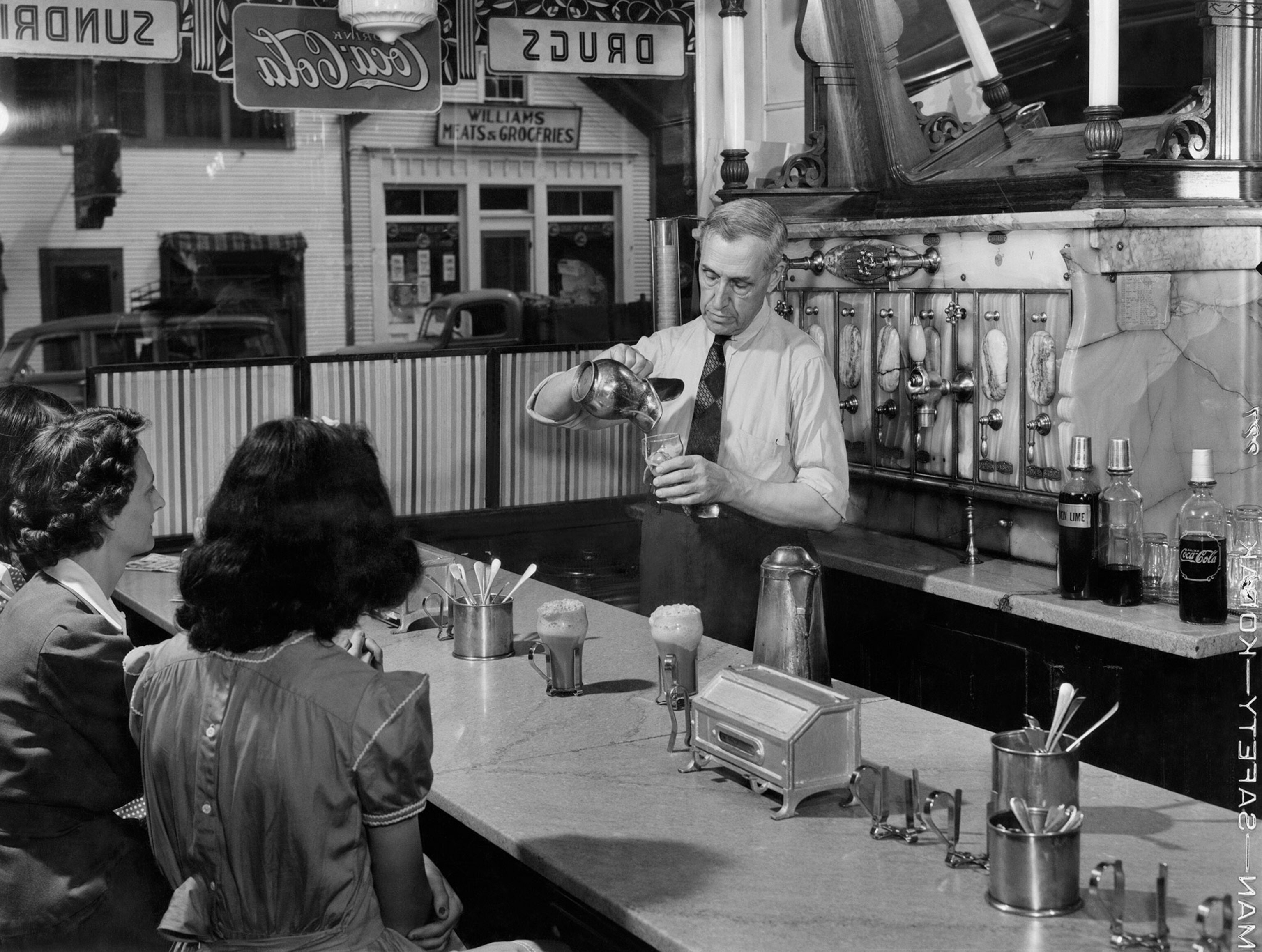 a druggist preparing ice cream floats at a soda fountain