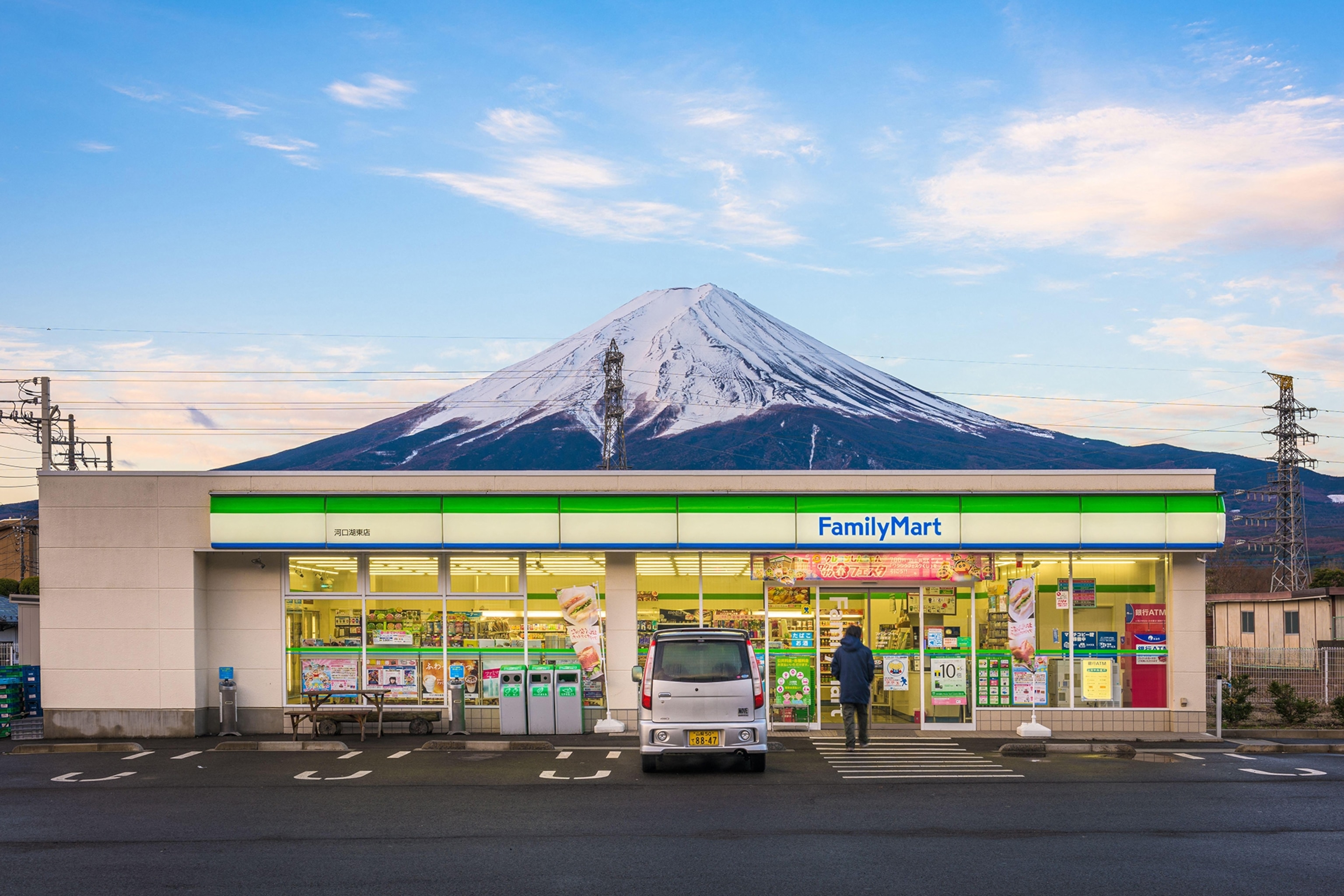 A convenience shop in front of Mount Fuji at early dusk.