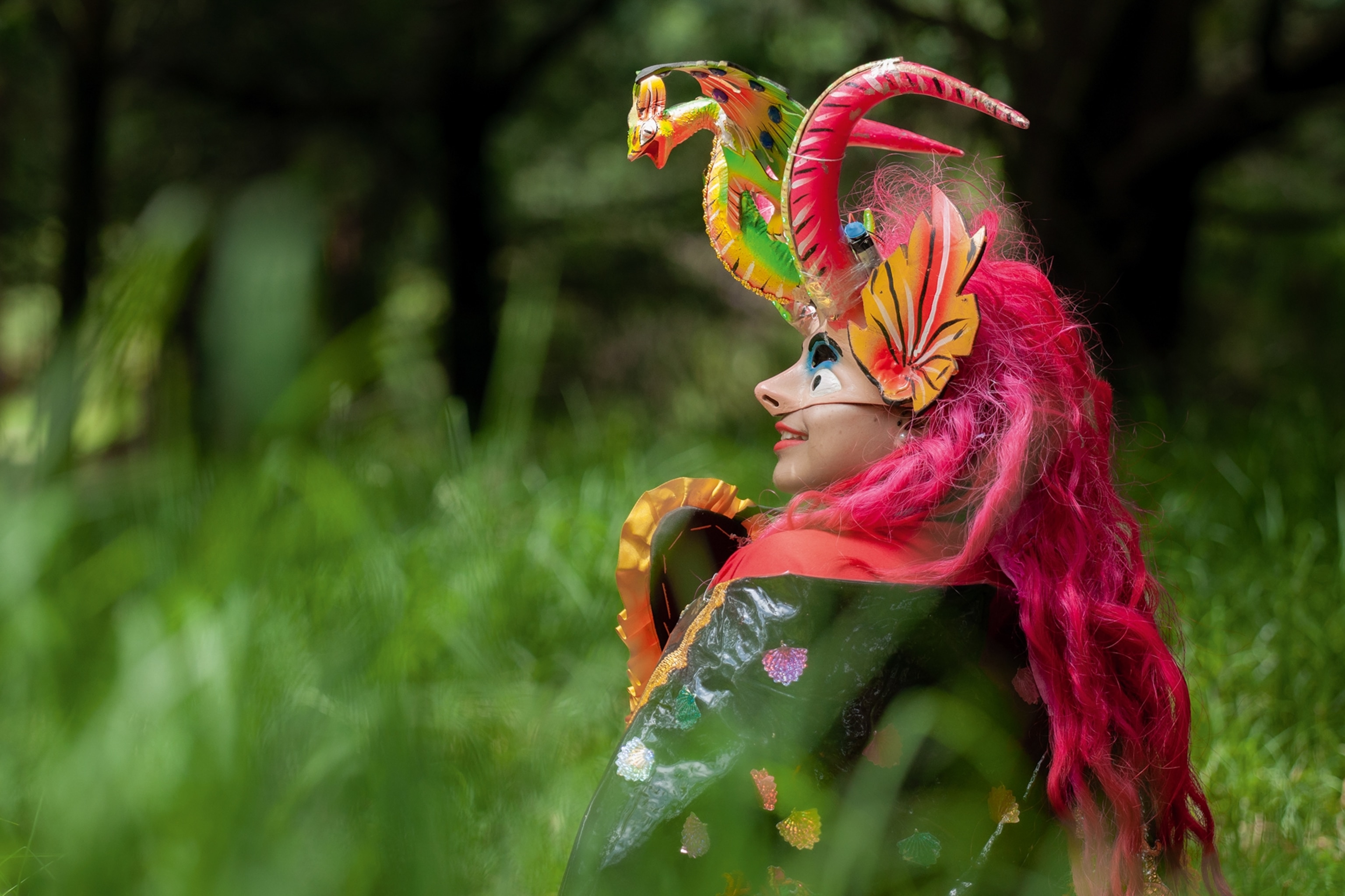 Person wears devil mask in field.