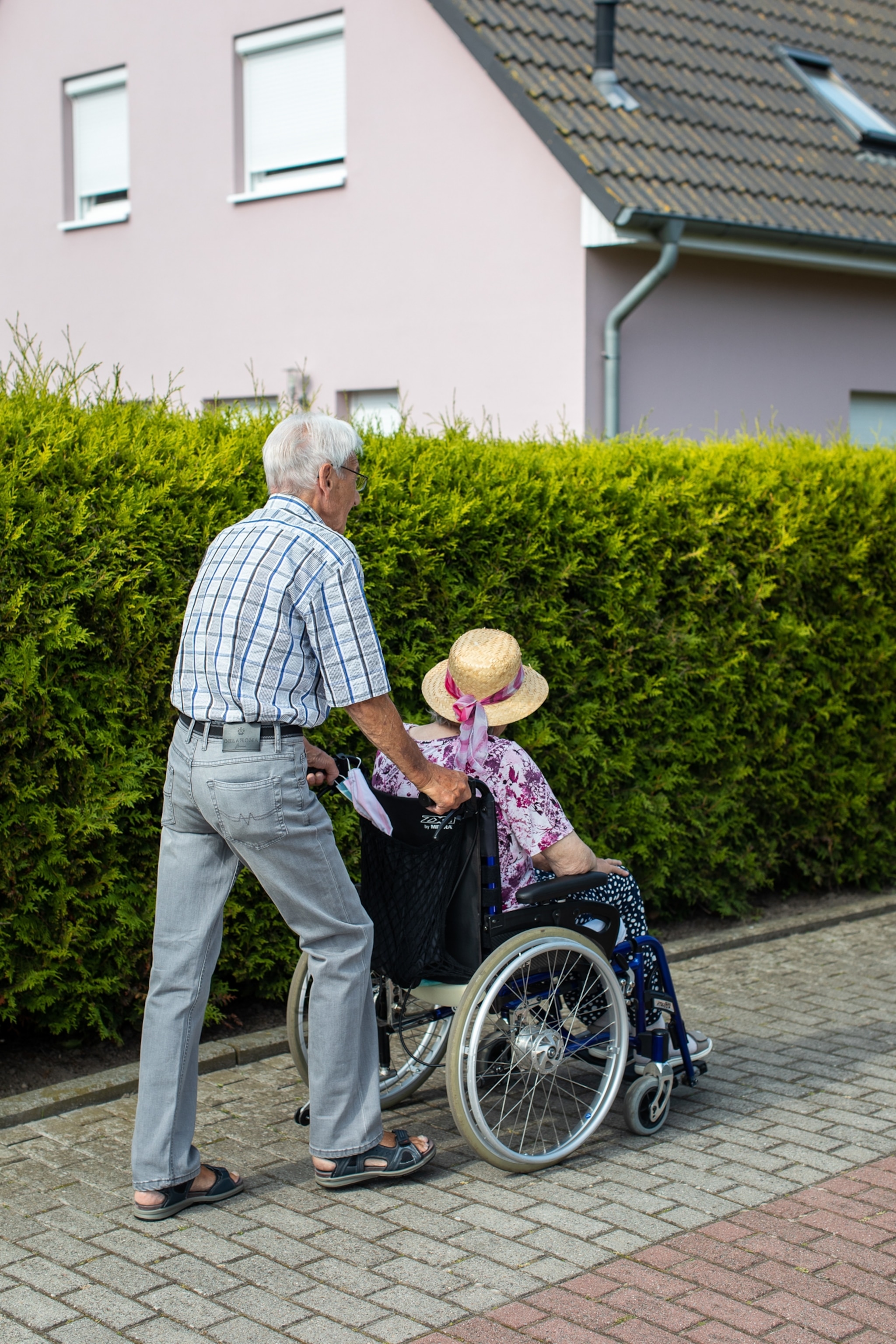 A Man pushes a wheel chair woth an elderly woman.