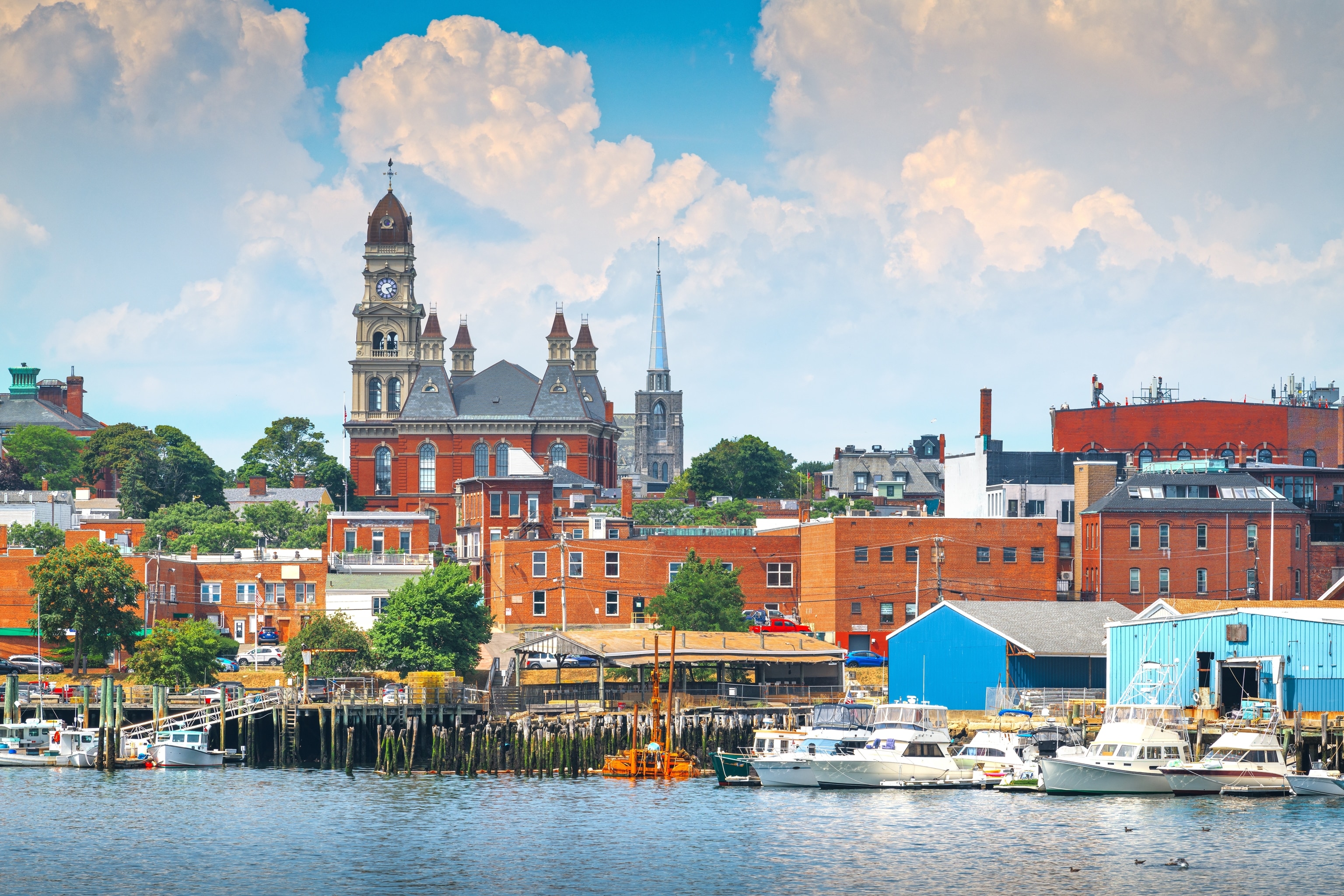 A city skyline view from the ocean, with boats passing by, of Gloucester, Massachusetts