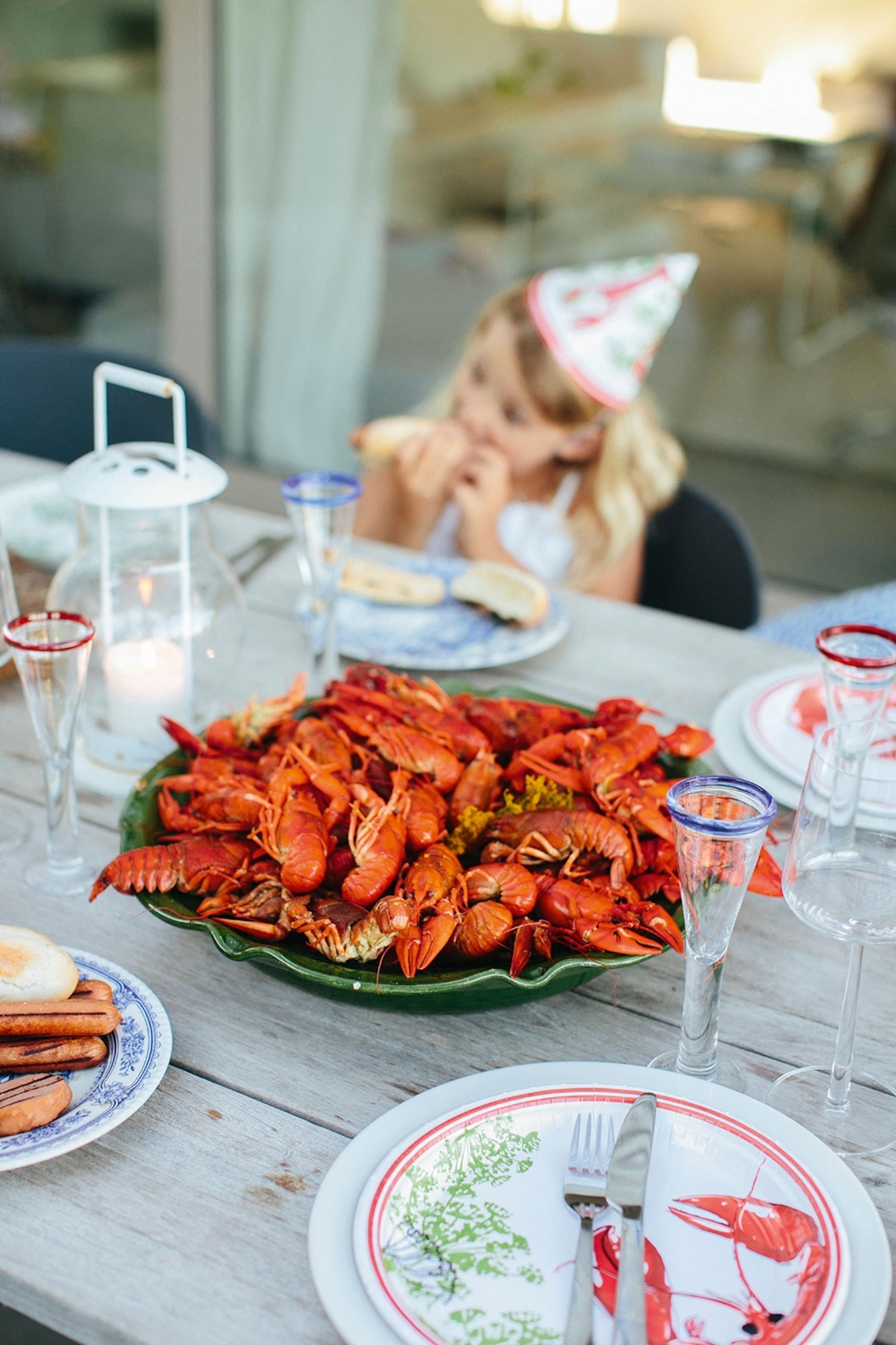 A large plate with stacked crayfish on a set wooden table in a garden.