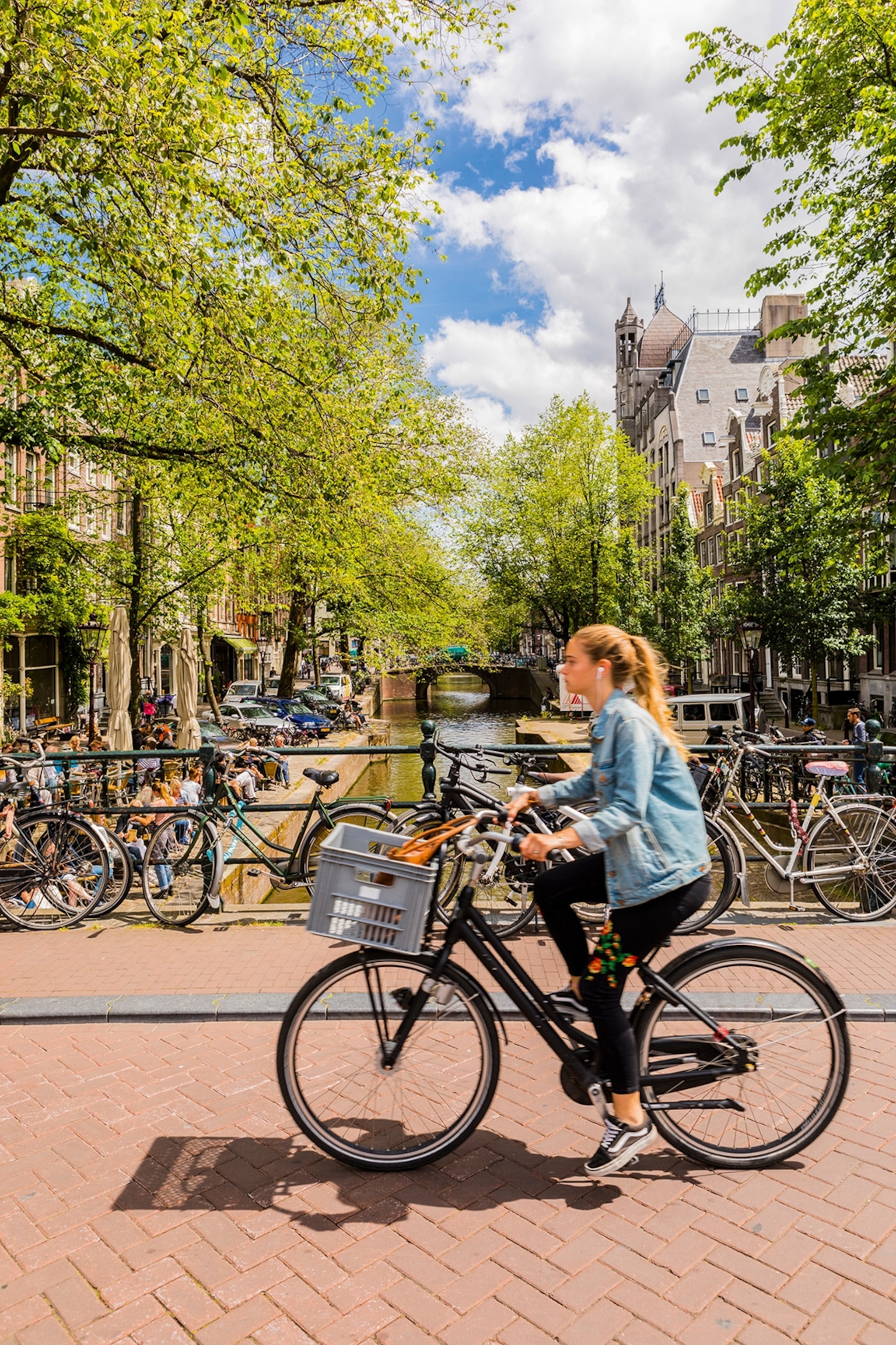 A young woman driving over a city canal with her bike.