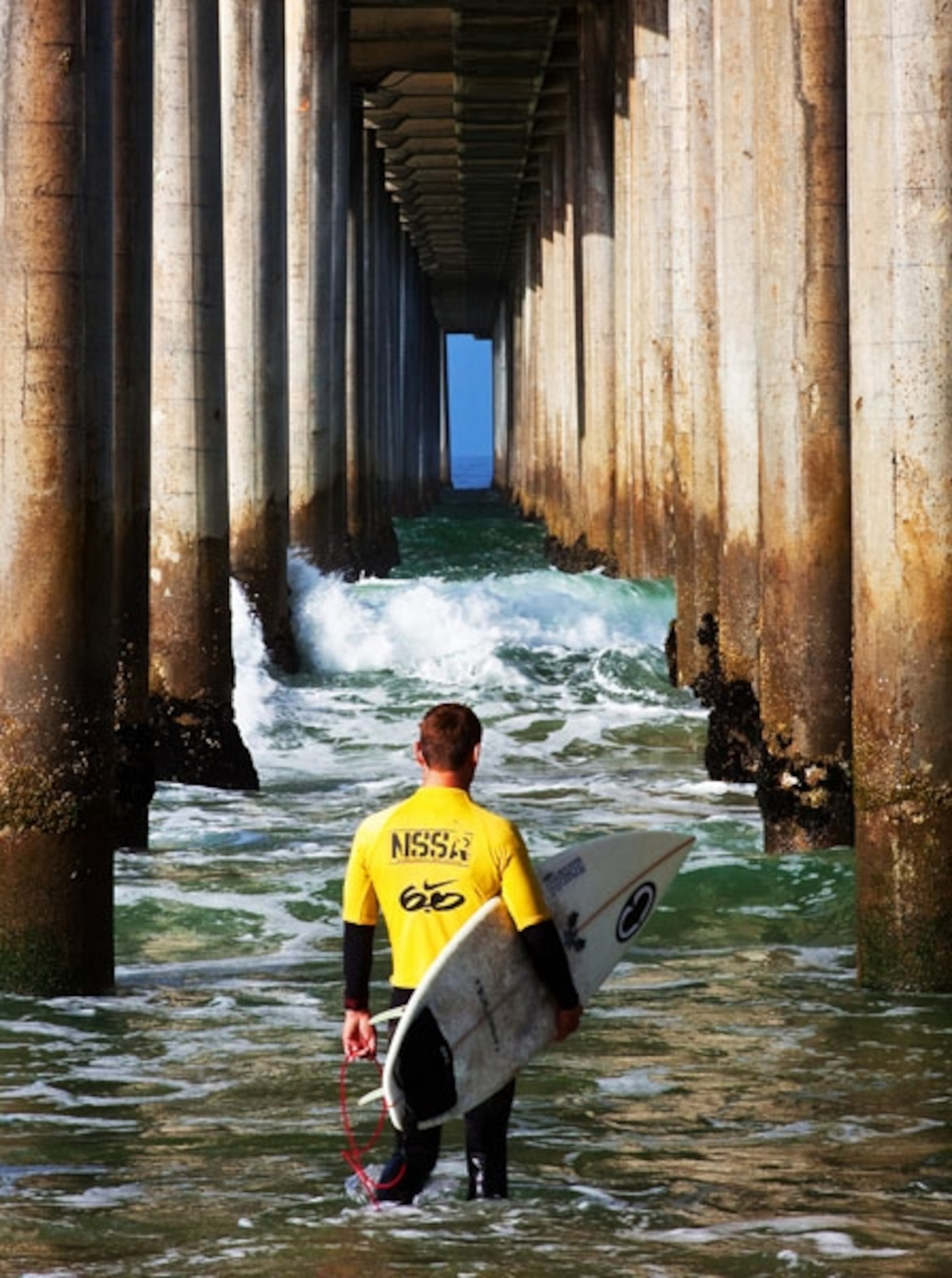 A surfer watches the waves under pier in Huntington Beach