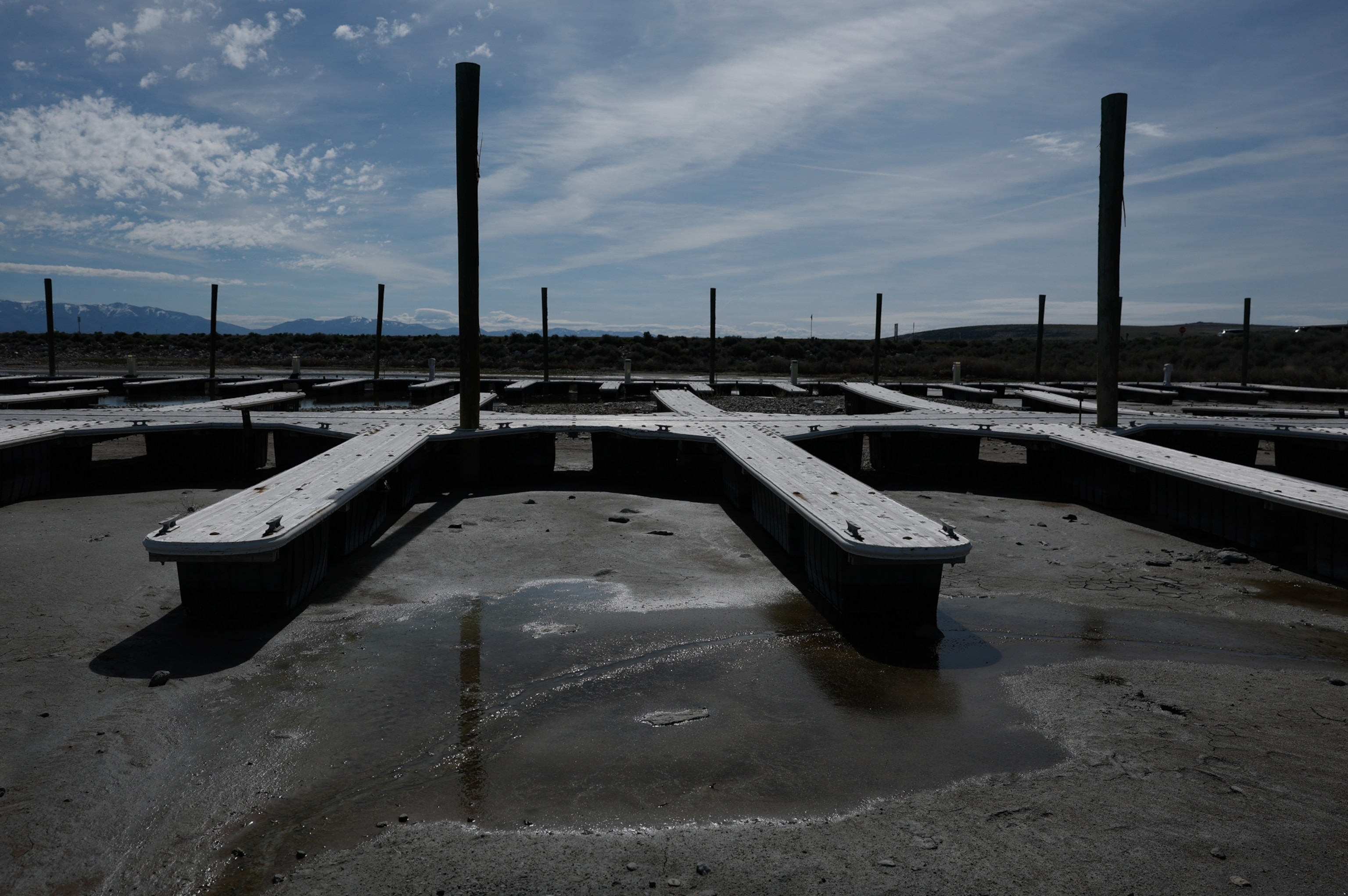 Empty, dry docks sit on cracked earth under a cloudy sky