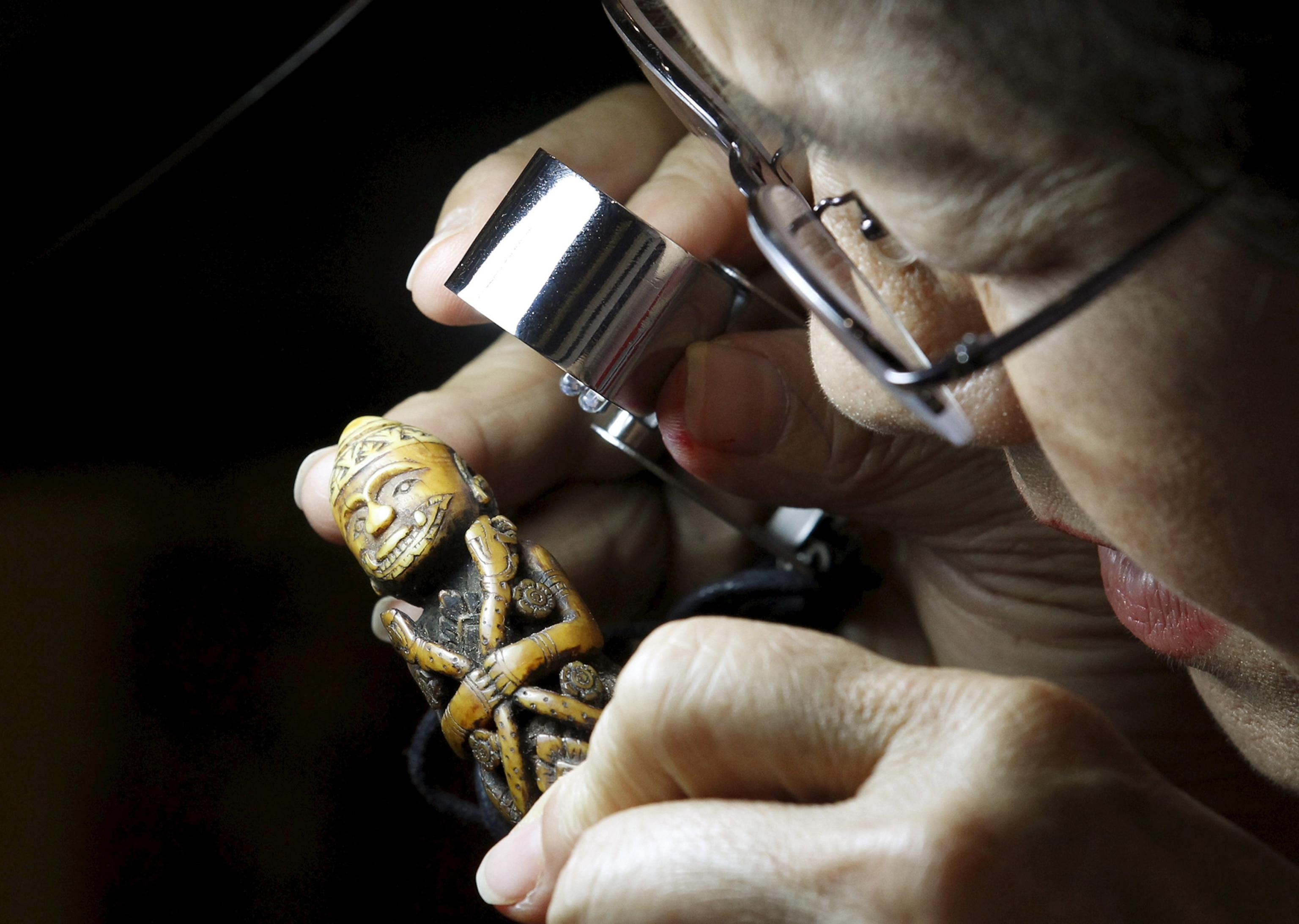 a woman inspecting a figure made of ivory
