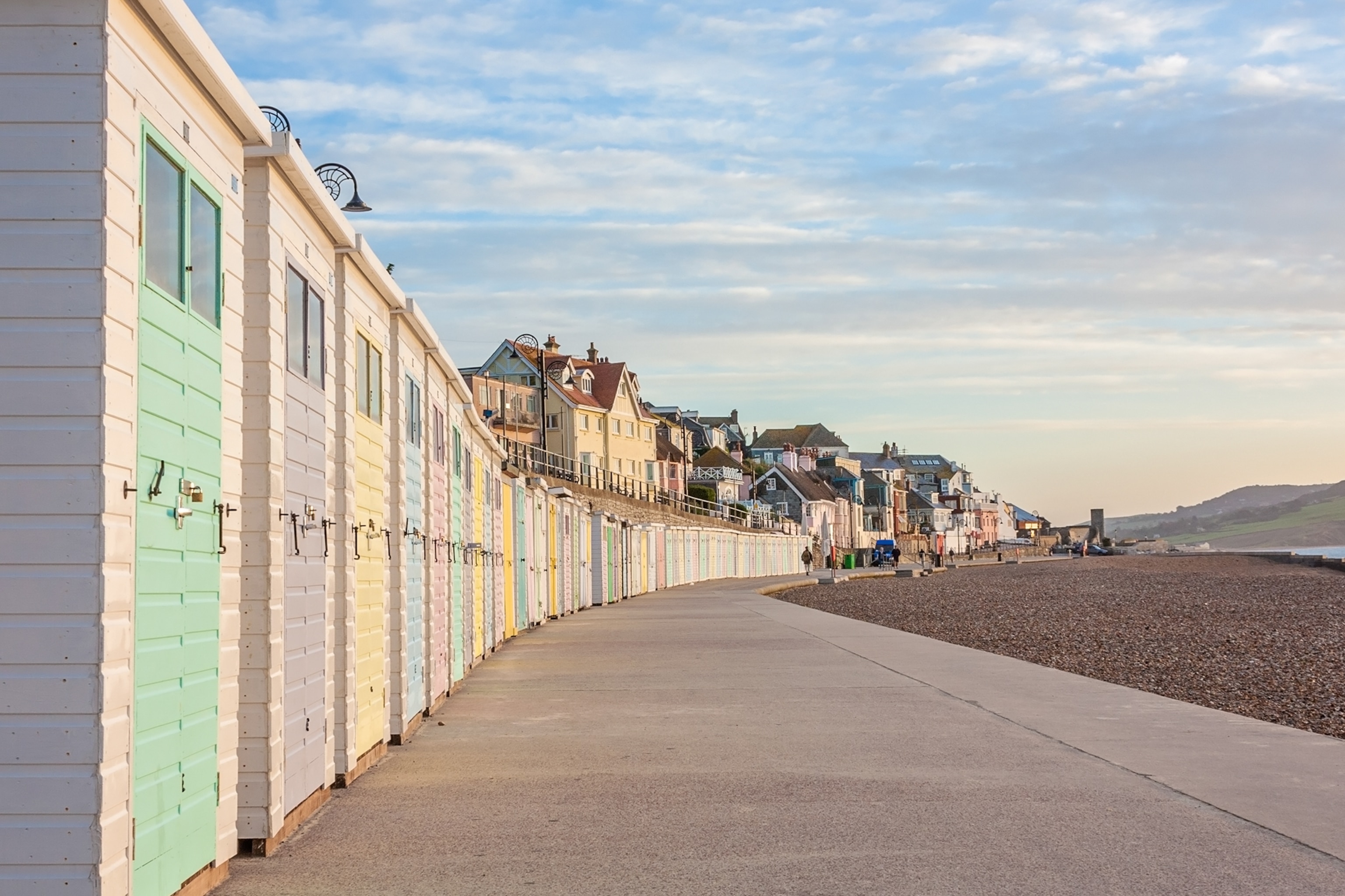 A seafront promenade with candy-coloured beach huts lining the beach.