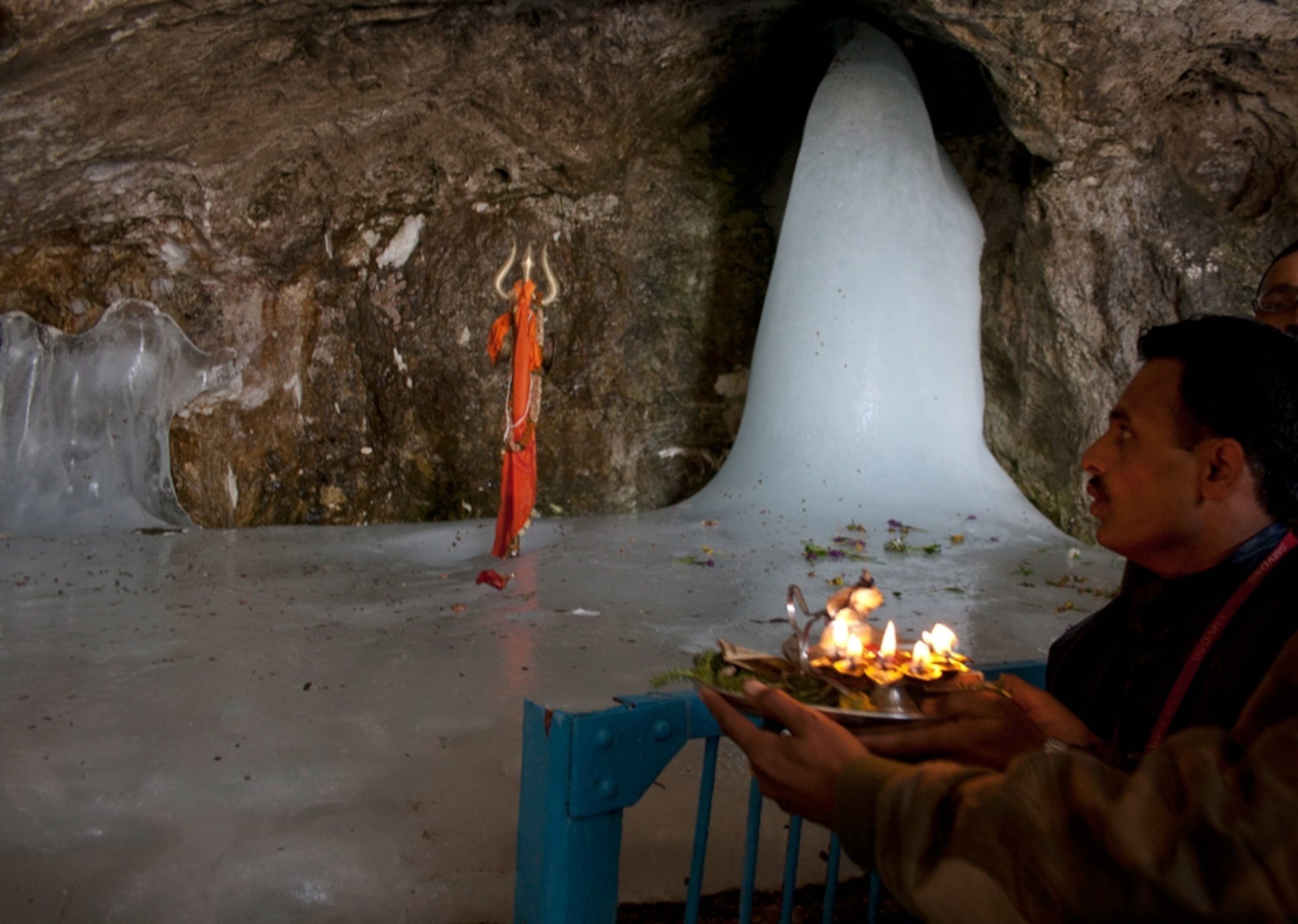 A Hindu pilgrim worships in front of an ice stalagmite, Shiva Lingam, a phallus symbol of the god Shiva during a pilgrimage to Amarnath