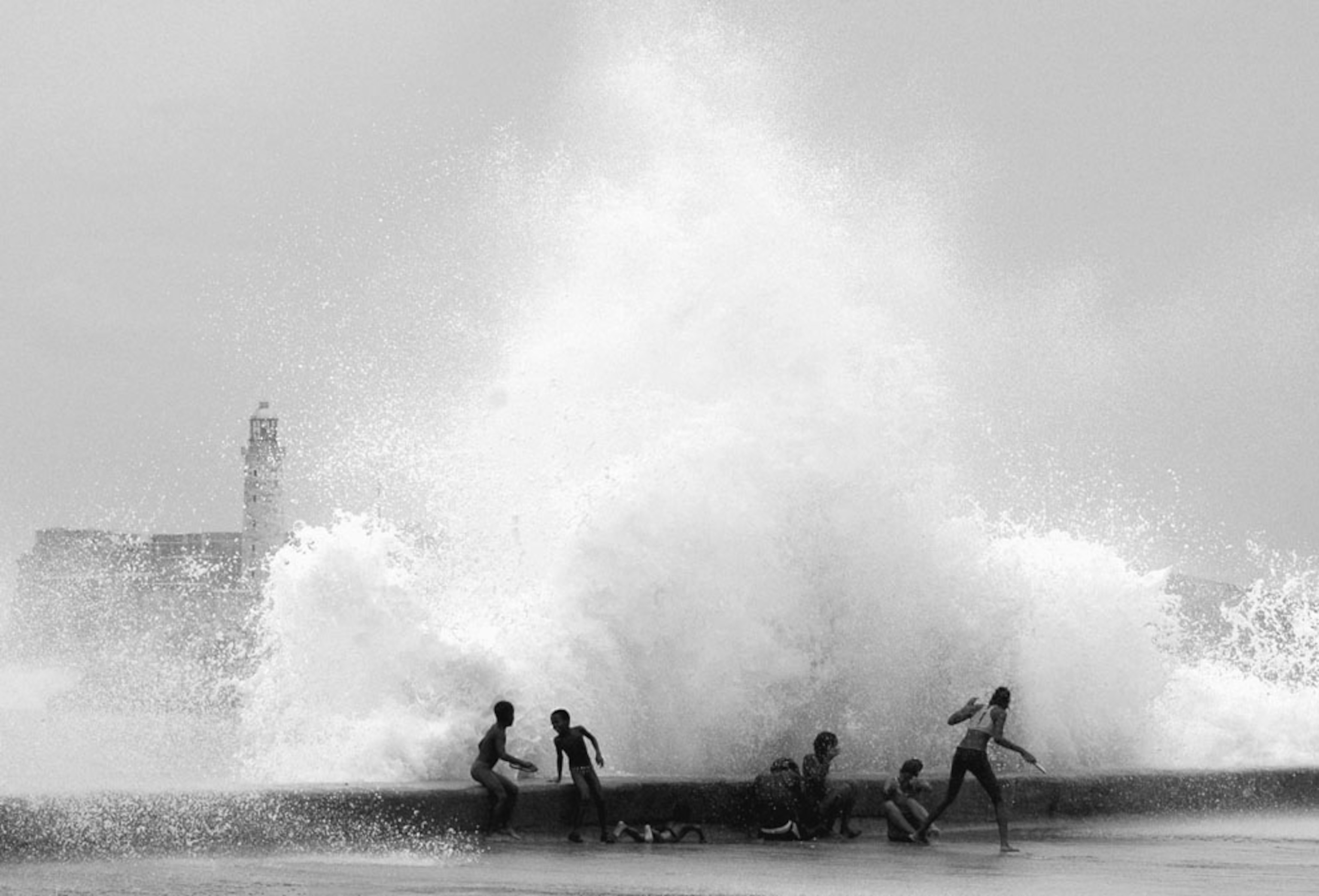 Children in Cuba play as a large wave from Hurricane Katrina crashes behind them