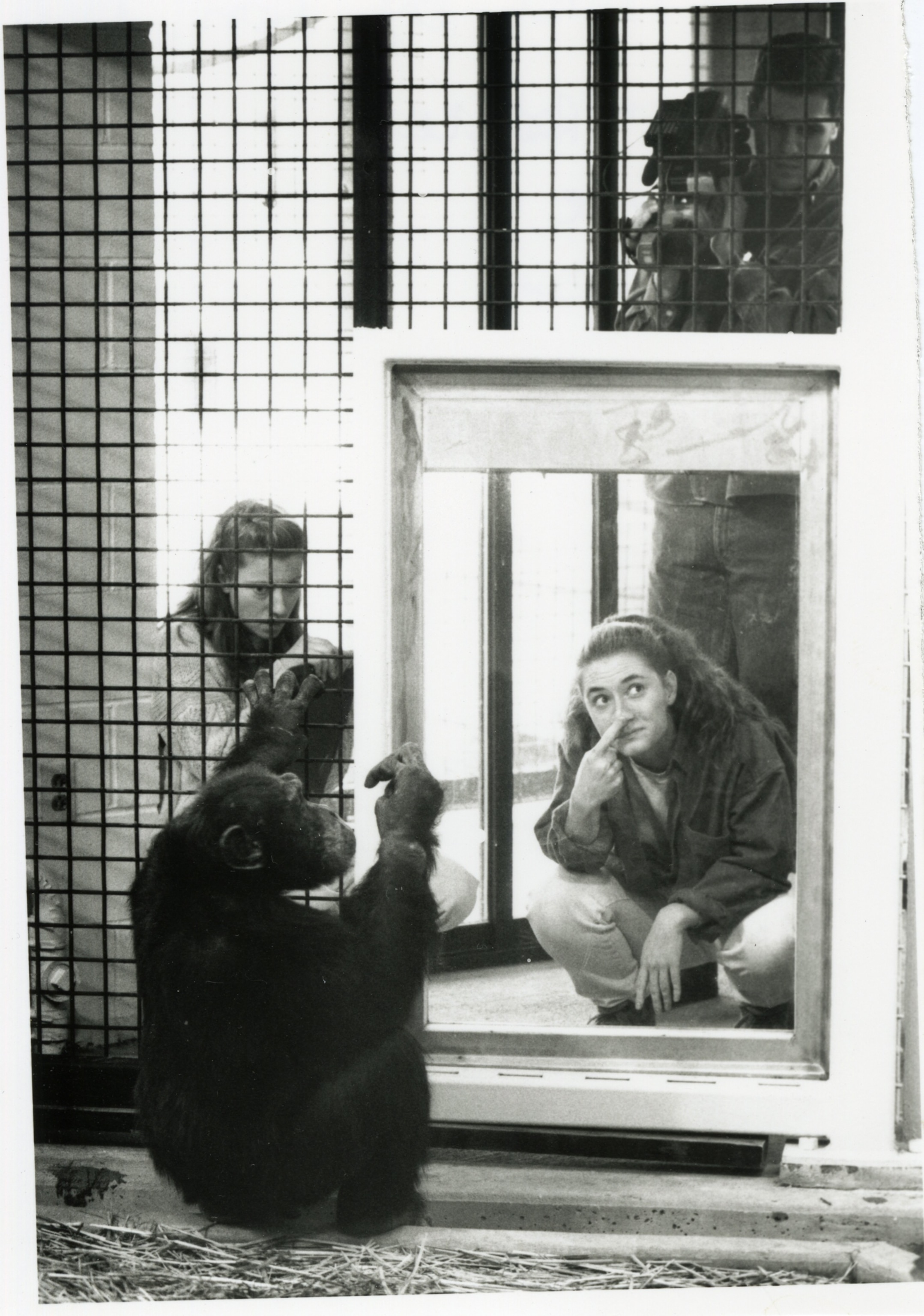 A black and white photograph of a woman with pale skin with a finger placed on her nose.