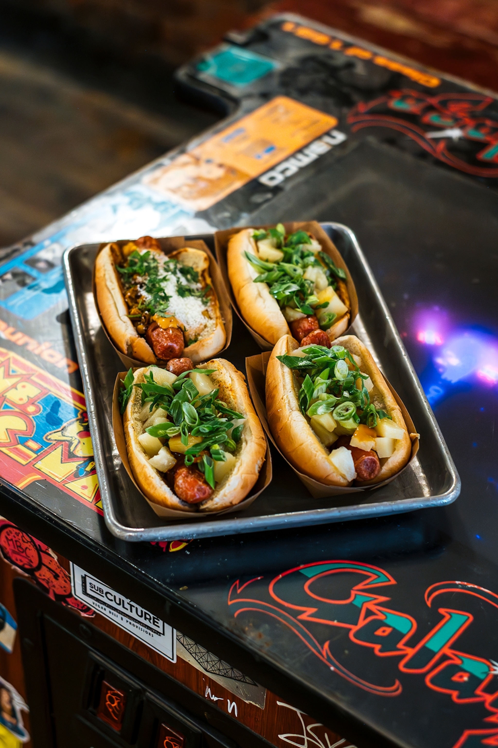 A tray of four hot dogs on a graffitied table.