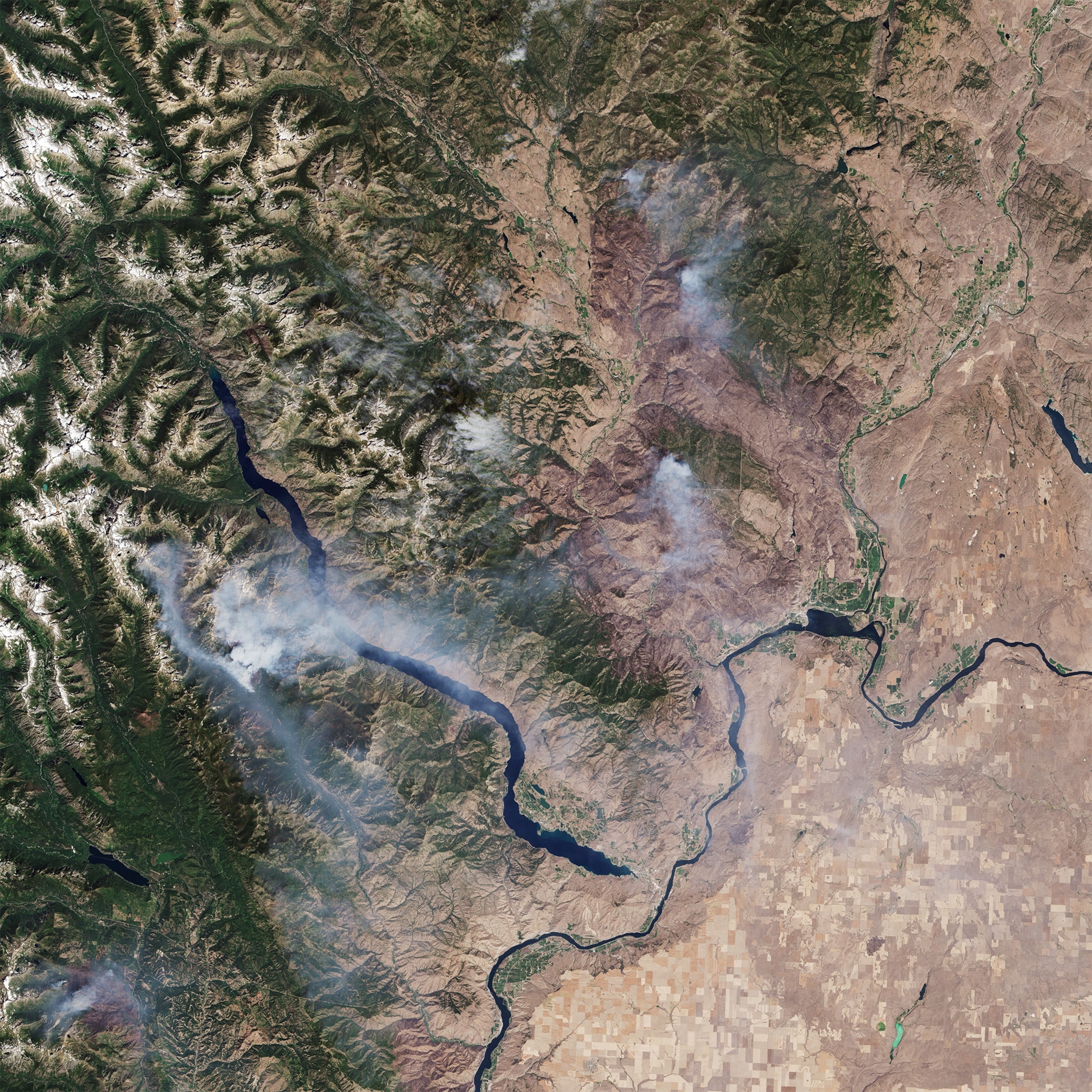 A Smokey Bear sign stands around earth that was scorched by a fire in Pateros, Washington.