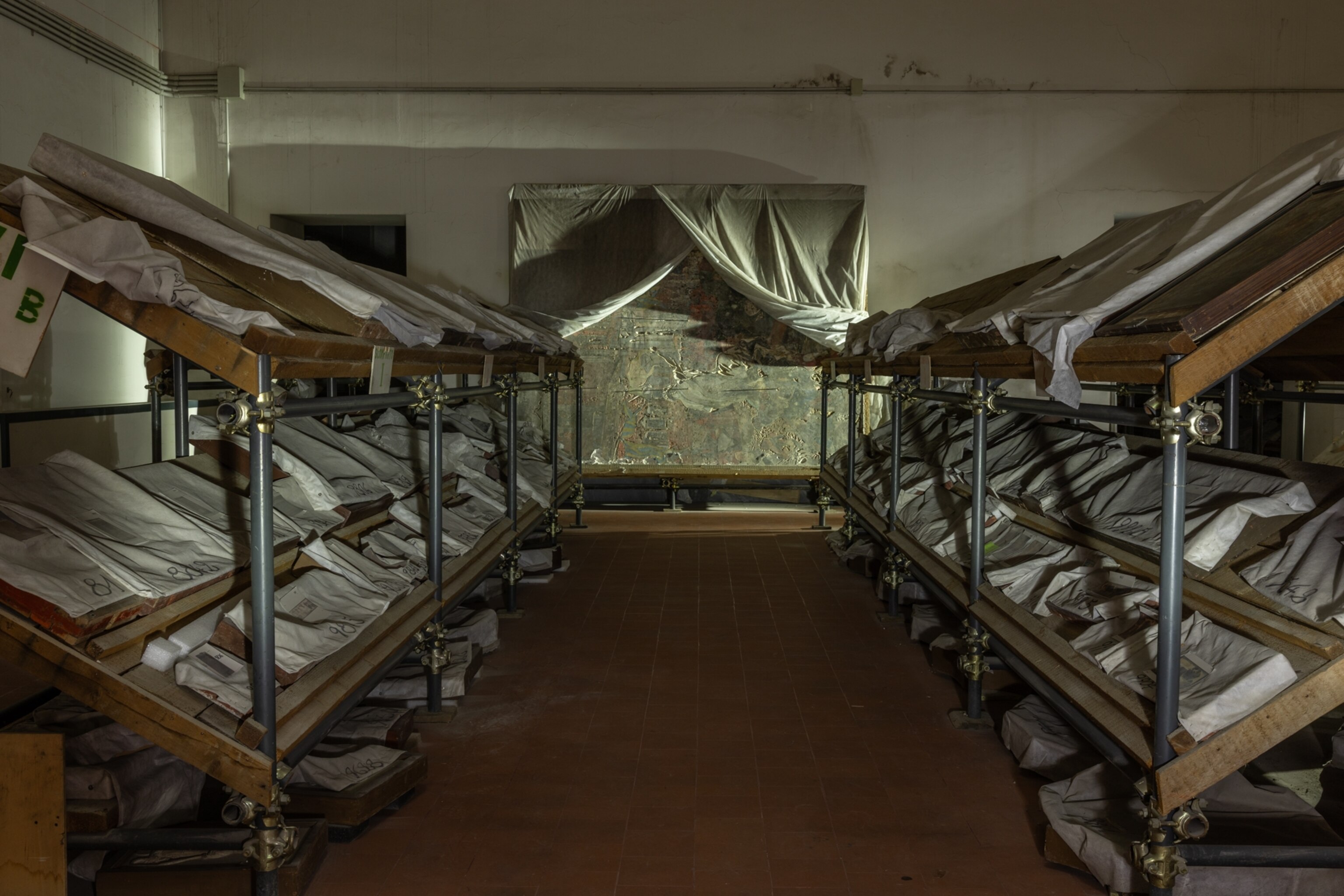 A room of shelves with sheets over paintings